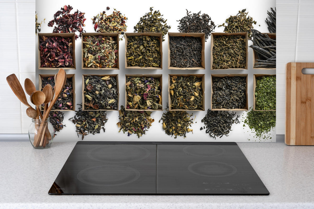 Spritzschutz - Gesunde Teesorten hinter einem Cerankochfeld zwischen Holz-Kochutensilien
