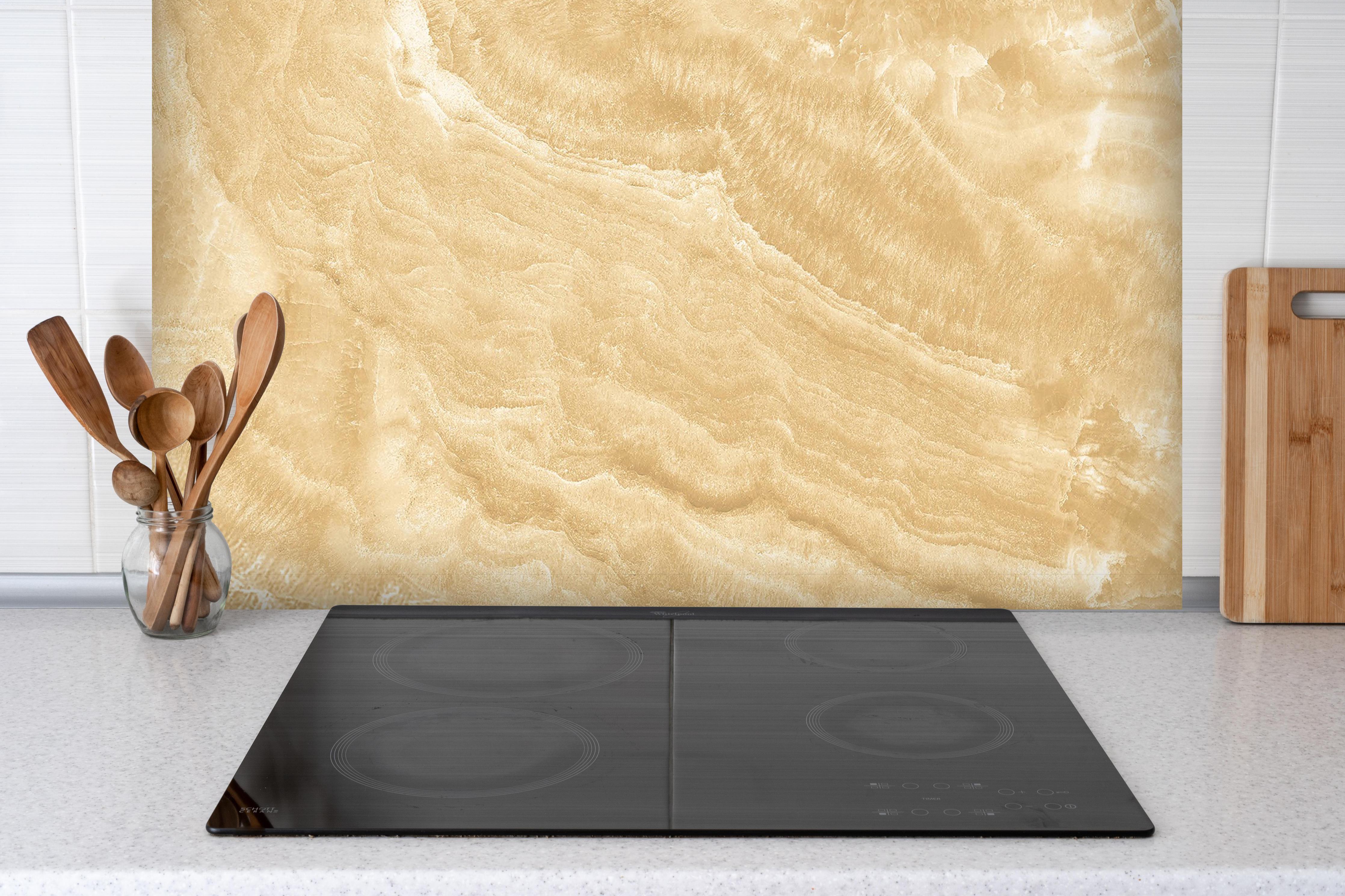 Spritzschutz - Goldener Marmor hinter einem Cerankochfeld zwischen Holz-Kochutensilien
