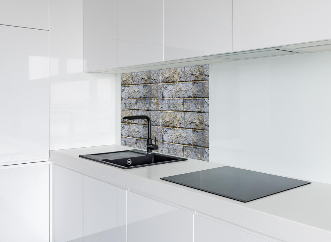 Spritzschutz - Graue Schnittsteinmauer hinter modernem schwarz-matten Spülbecken in weißer Hochglanz-Küche