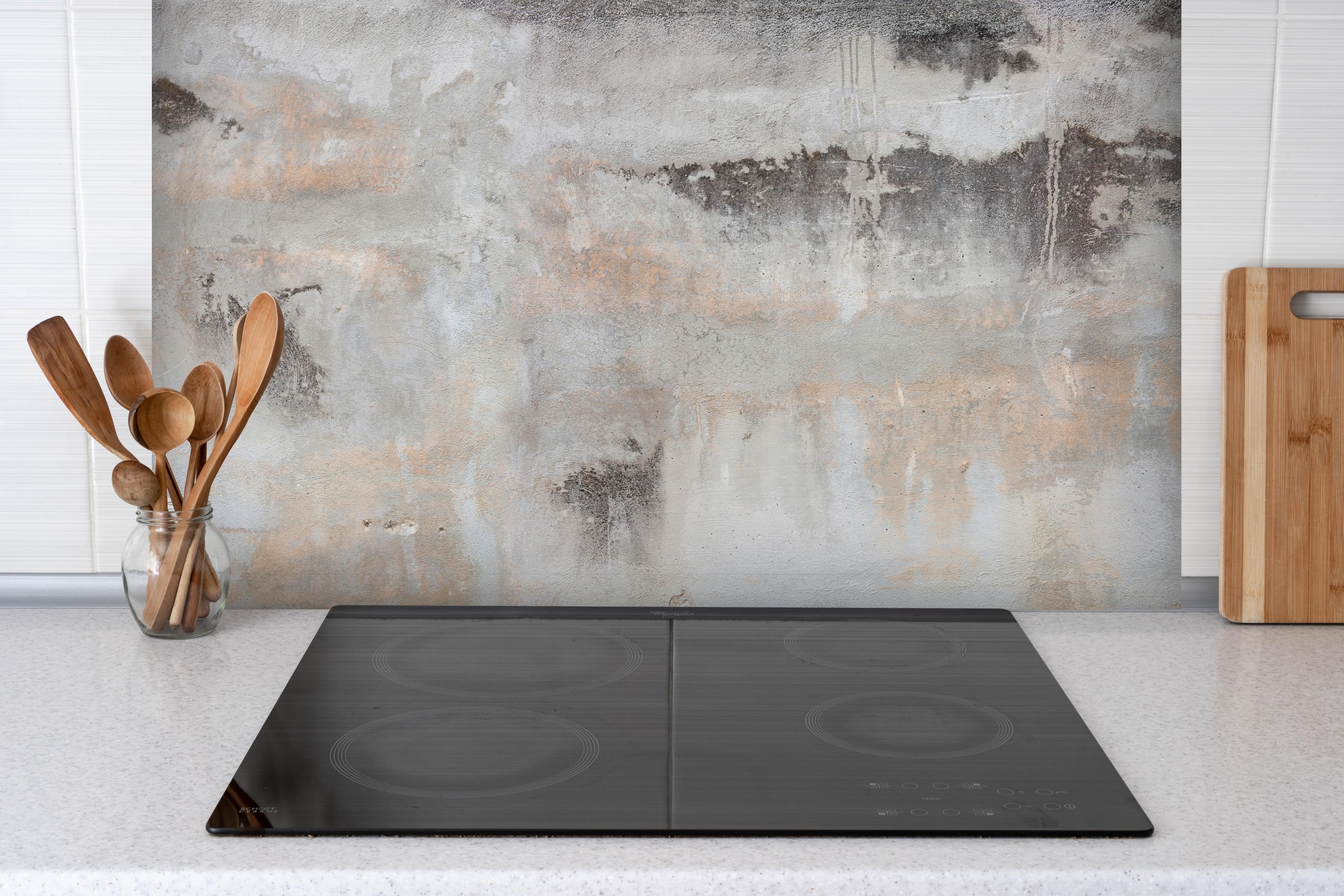 Spritzschutz - Grunge Betonwand hinter einem Cerankochfeld zwischen Holz-Kochutensilien
