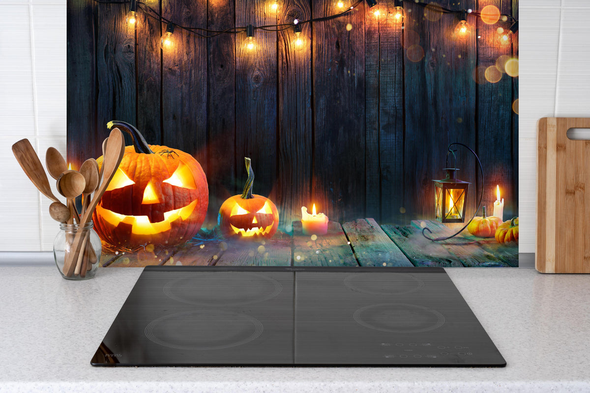Spritzschutz - Halloween - Kerzen und Lichterketten hinter einem Cerankochfeld zwischen Holz-Kochutensilien
