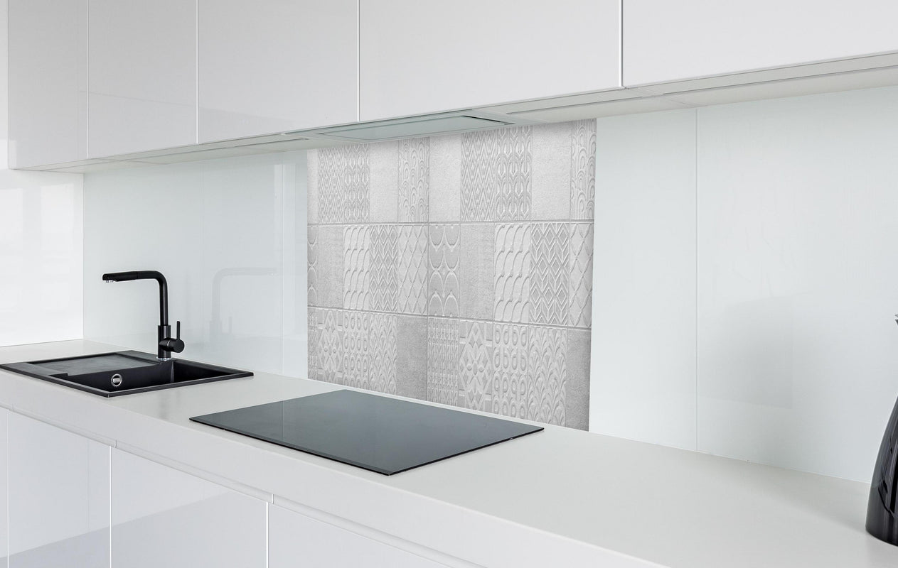 Spritzschutz - Hellgraue quadratische Mosaik  in weißer Hochglanz-Küche hinter einem Cerankochfeld