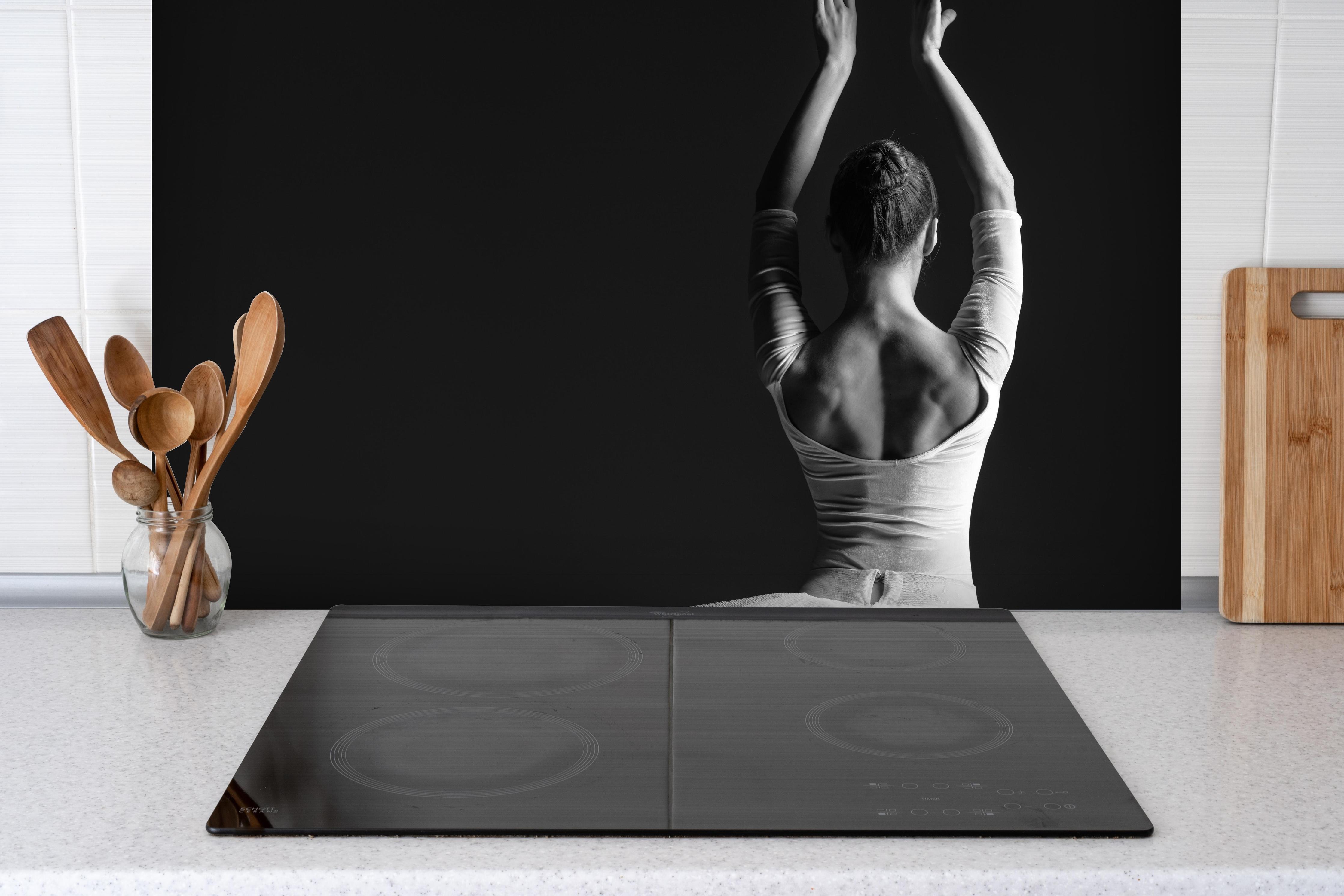 Spritzschutz - Junge posierende Ballerina hinter einem Cerankochfeld zwischen Holz-Kochutensilien
