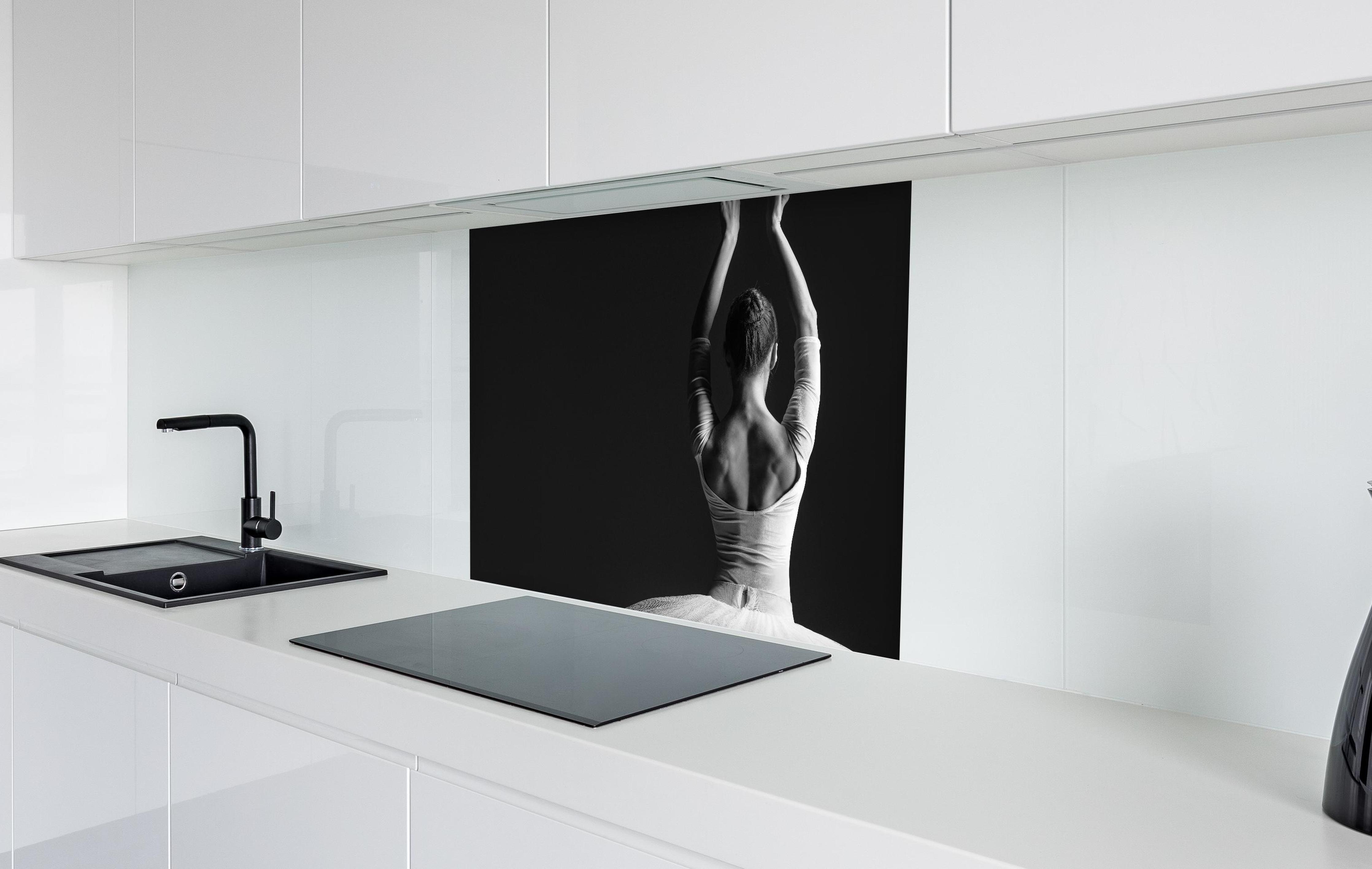 Spritzschutz - Junge posierende Ballerina  in weißer Hochglanz-Küche hinter einem Cerankochfeld