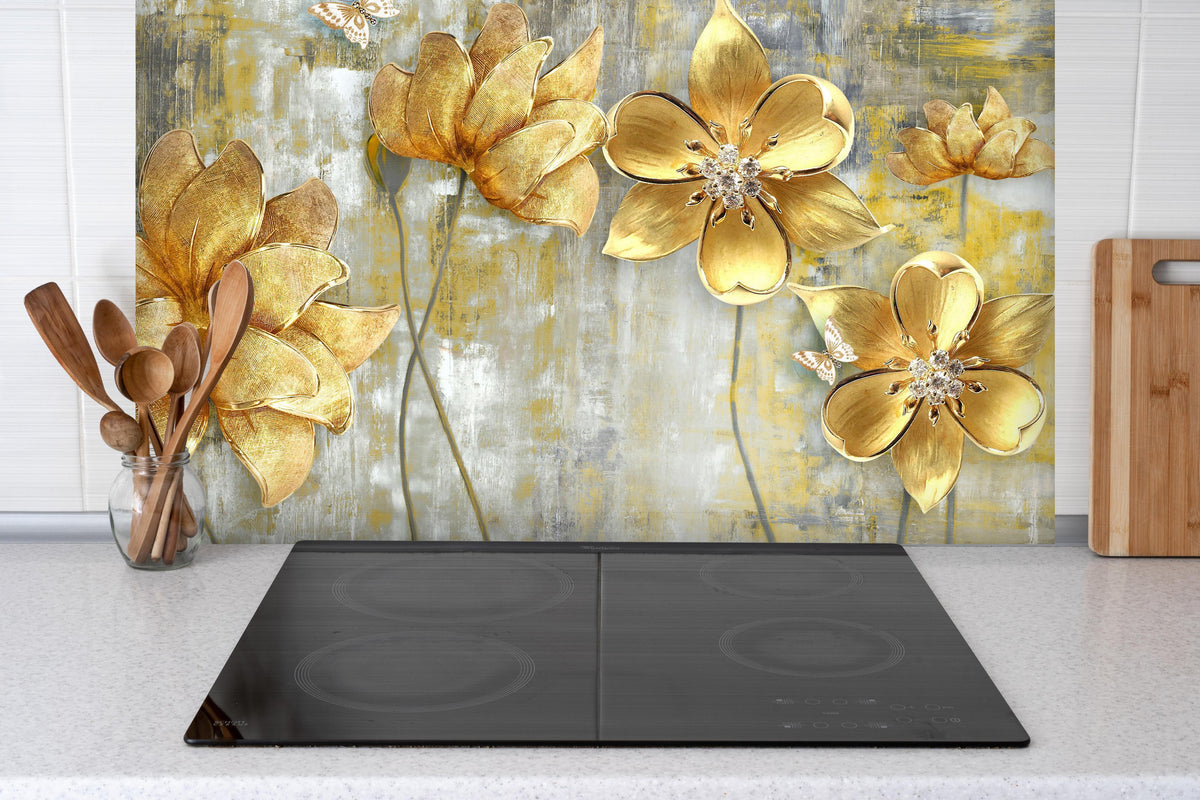 Spritzschutz - Künstlerische Blattgold-Blumen hinter einem Cerankochfeld zwischen Holz-Kochutensilien
