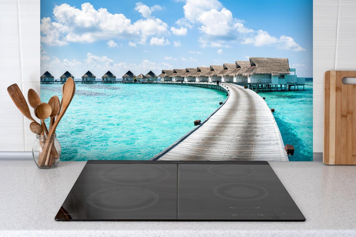 Spritzschutz - Malediven Wasser-Hotel hinter einem Cerankochfeld zwischen Holz-Kochutensilien
