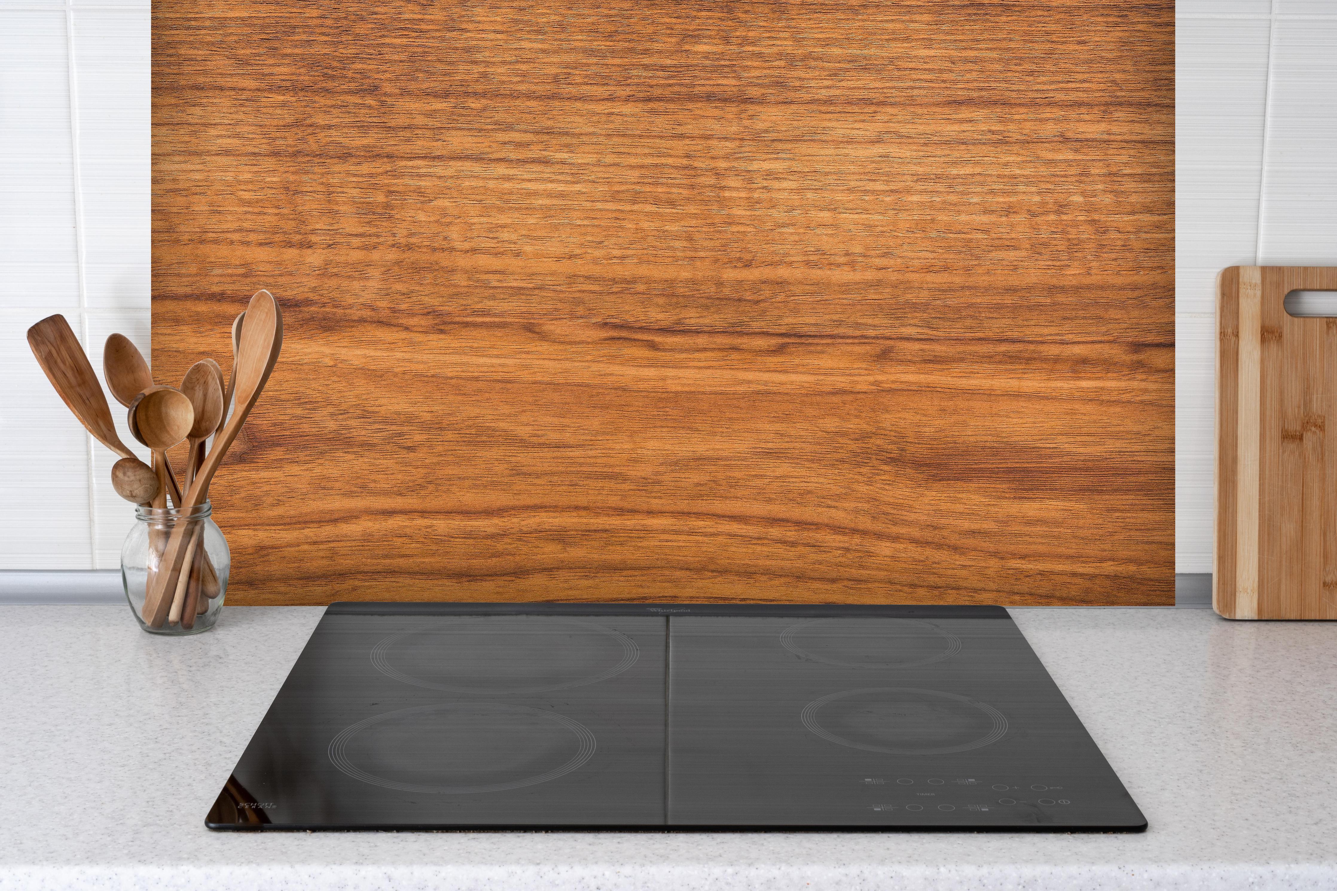 Spritzschutz - Natürliches sattes Eichenholz hinter einem Cerankochfeld zwischen Holz-Kochutensilien
