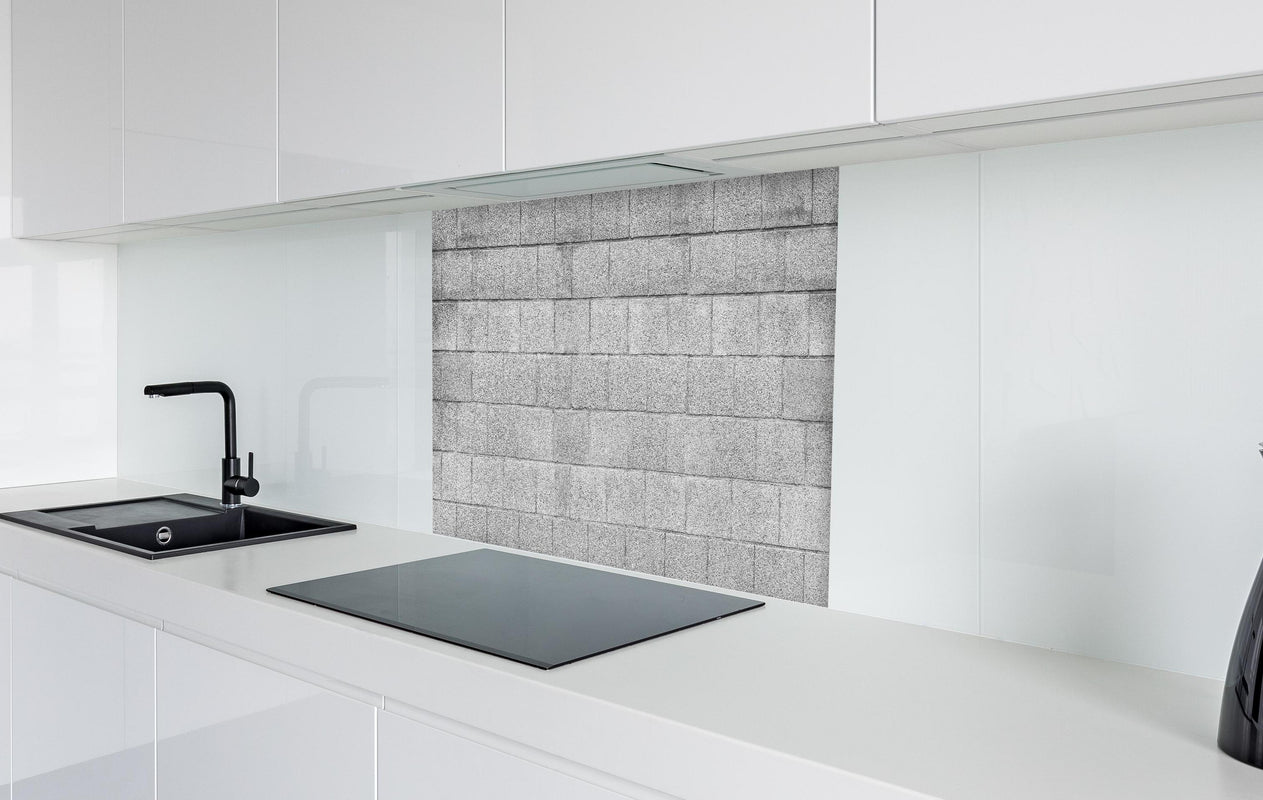 Spritzschutz - Panorama der grauen Zementblockwand  in weißer Hochglanz-Küche hinter einem Cerankochfeld
