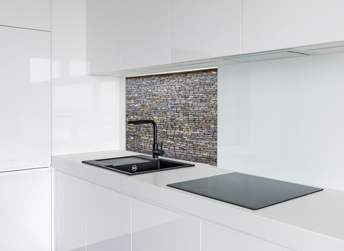 Spritzschutz - Pastellfarbene Steinmauer hinter modernem schwarz-matten Spülbecken in weißer Hochglanz-Küche