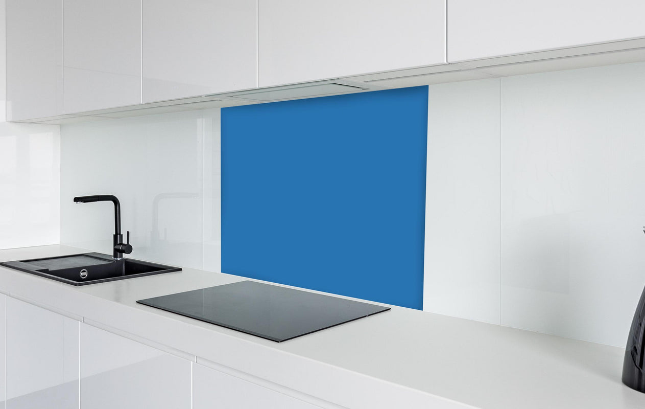 Spritzschutz - RAL 5015 (Himmelblau)  in weißer Hochglanz-Küche hinter einem Cerankochfeld