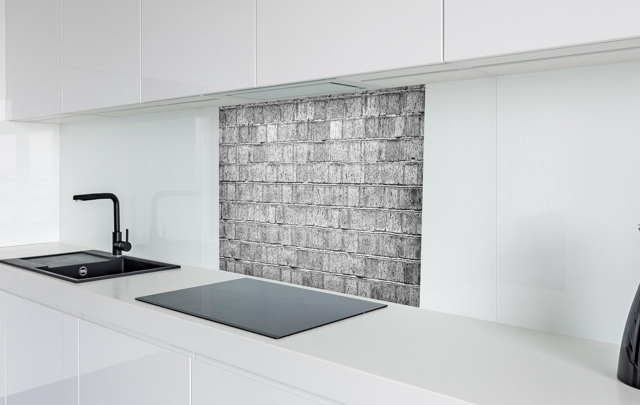 Spritzschutz - Raues hellgraues Mauerwerk  in weißer Hochglanz-Küche hinter einem Cerankochfeld