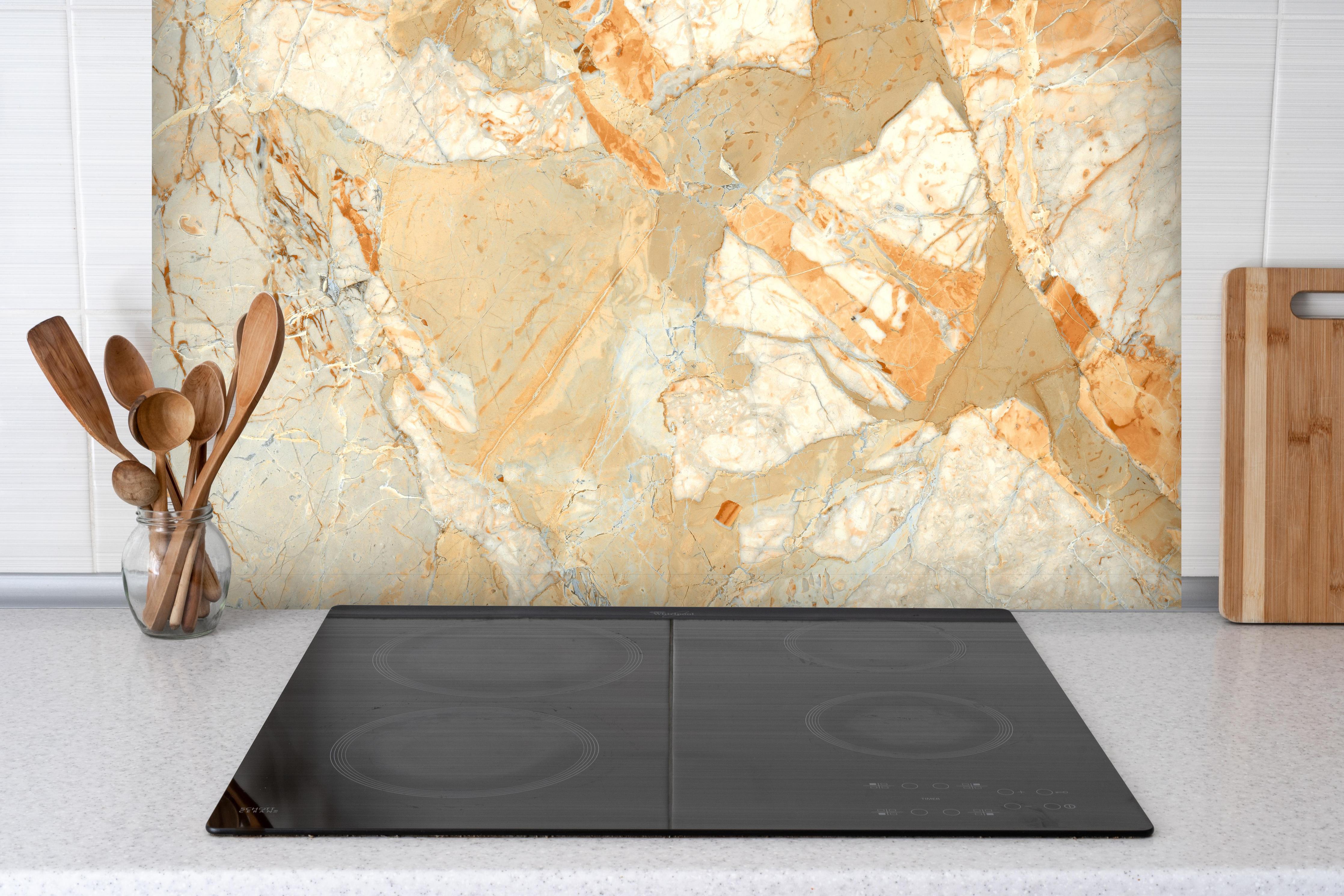 Spritzschutz - Rötlich-beiger rissiger Marmor hinter einem Cerankochfeld zwischen Holz-Kochutensilien
