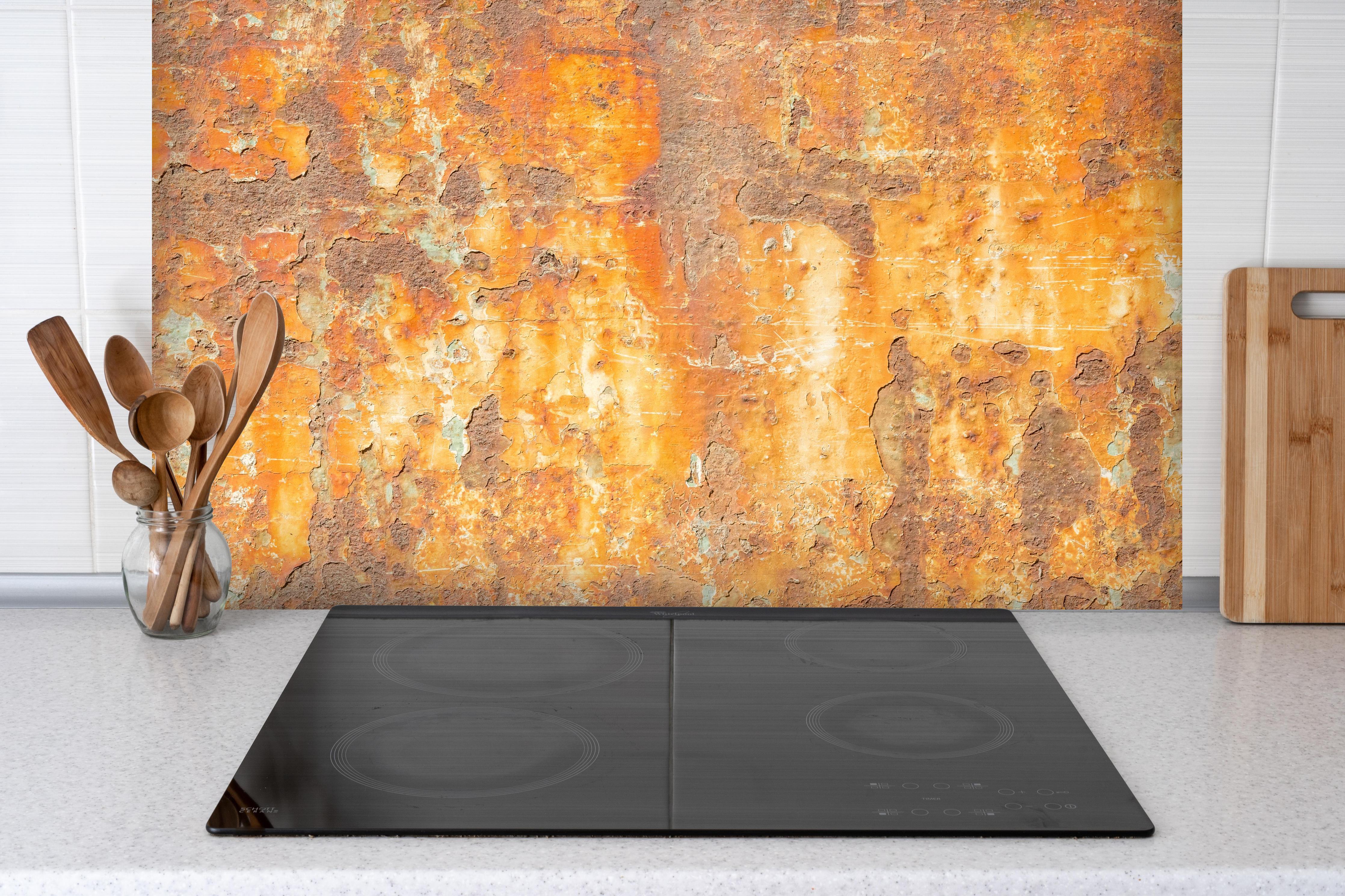 Spritzschutz - Rostige Betonwand hinter einem Cerankochfeld zwischen Holz-Kochutensilien

