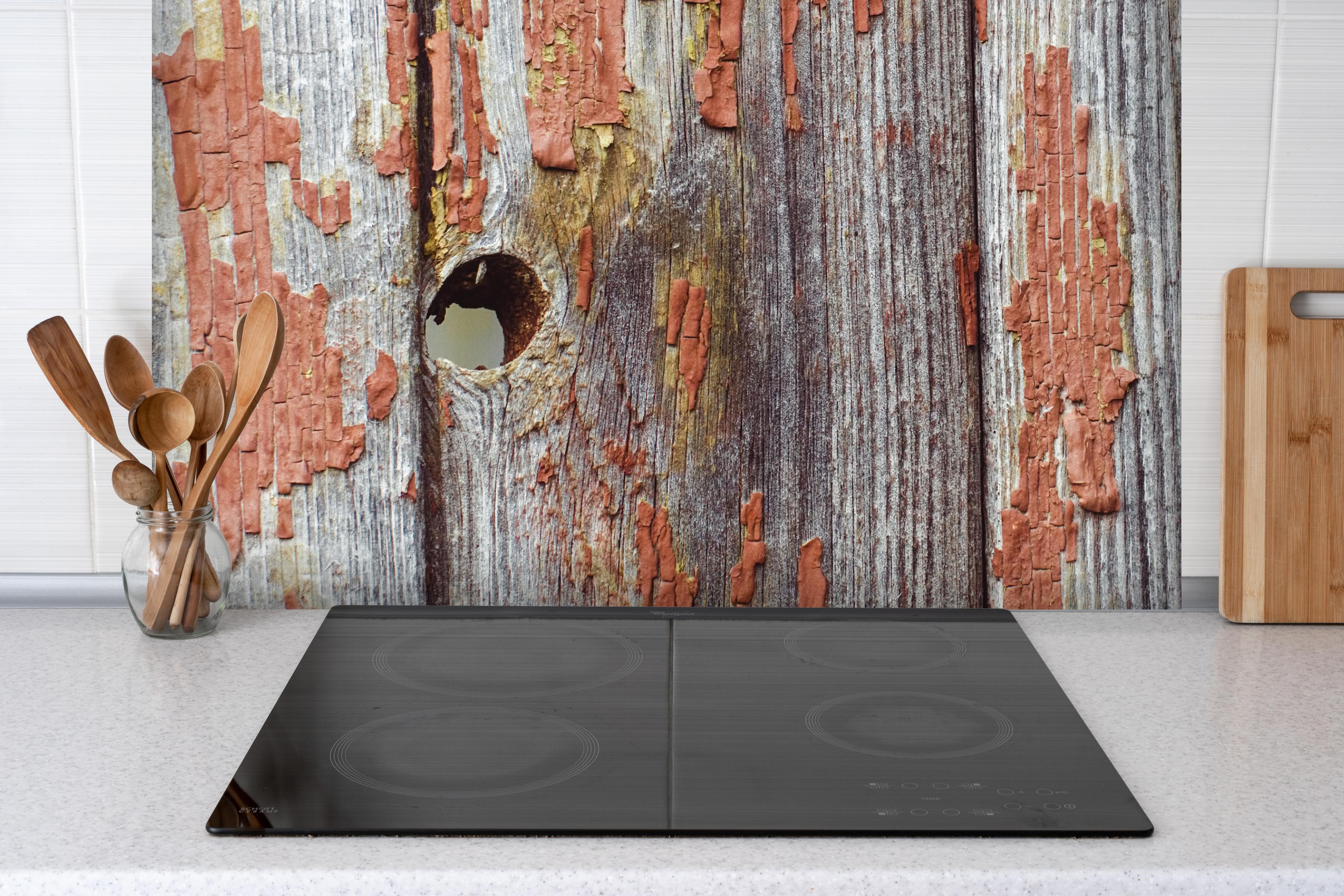 Spritzschutz - Rustikale Holzbretter mit Loch hinter einem Cerankochfeld zwischen Holz-Kochutensilien
