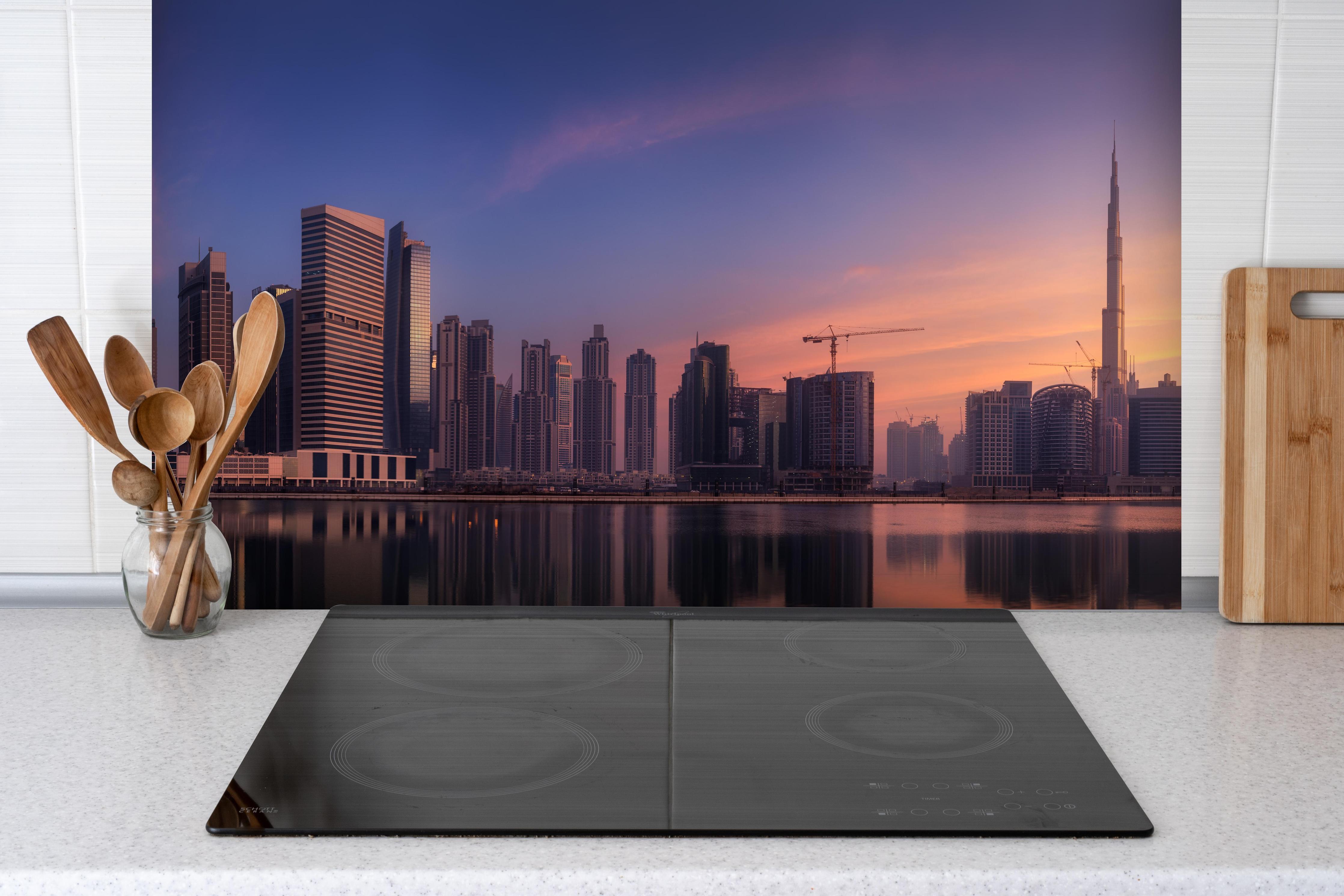Spritzschutz - Schönes Stadtbild von Dubai hinter einem Cerankochfeld zwischen Holz-Kochutensilien

