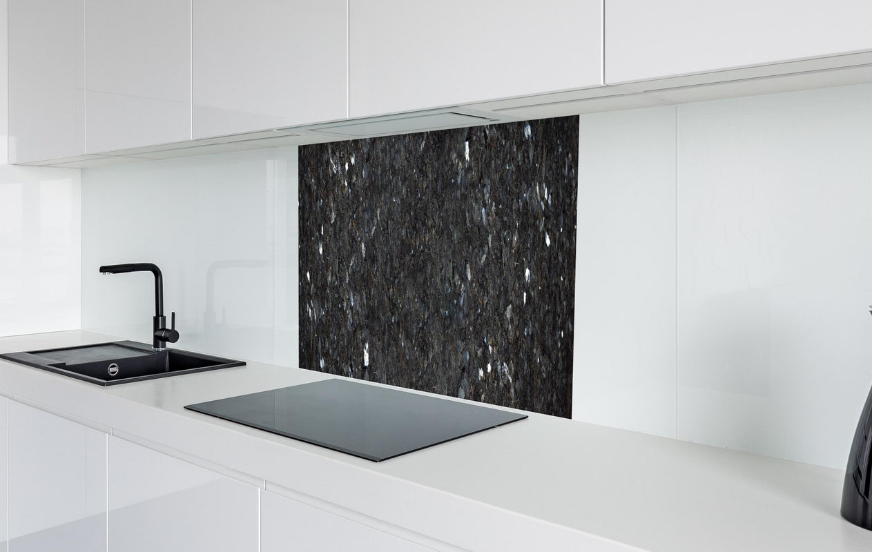 Spritzschutz - Schwarze Granitwand  in weißer Hochglanz-Küche hinter einem Cerankochfeld