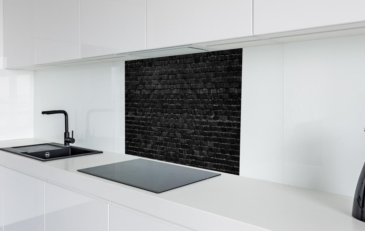 Spritzschutz - Schwarze raue Ziegelwand  in weißer Hochglanz-Küche hinter einem Cerankochfeld