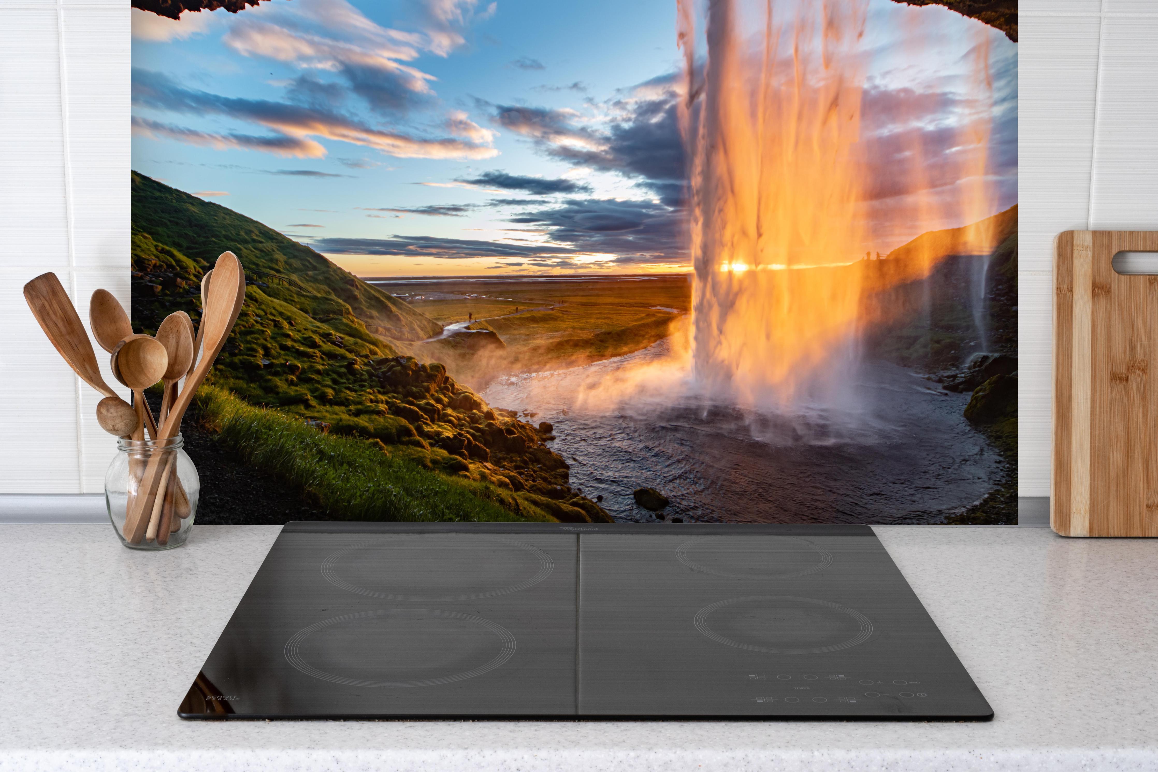 Spritzschutz - Seljalandsfoss Wasserfall in Island bei Sonnenuntergang hinter einem Cerankochfeld zwischen Holz-Kochutensilien
