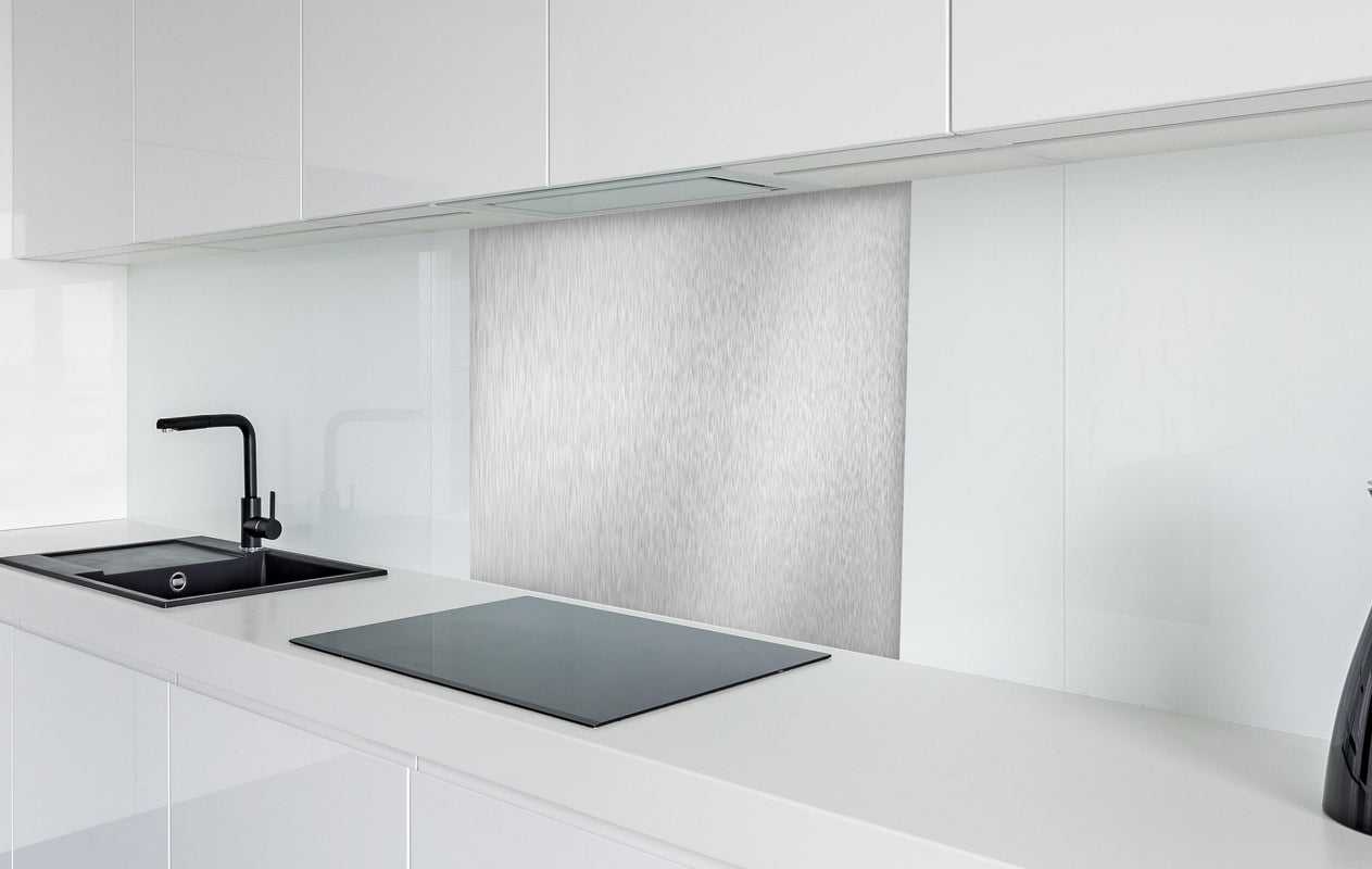 Spritzschutz - Silberne belichtete Oberfläche  in weißer Hochglanz-Küche hinter einem Cerankochfeld