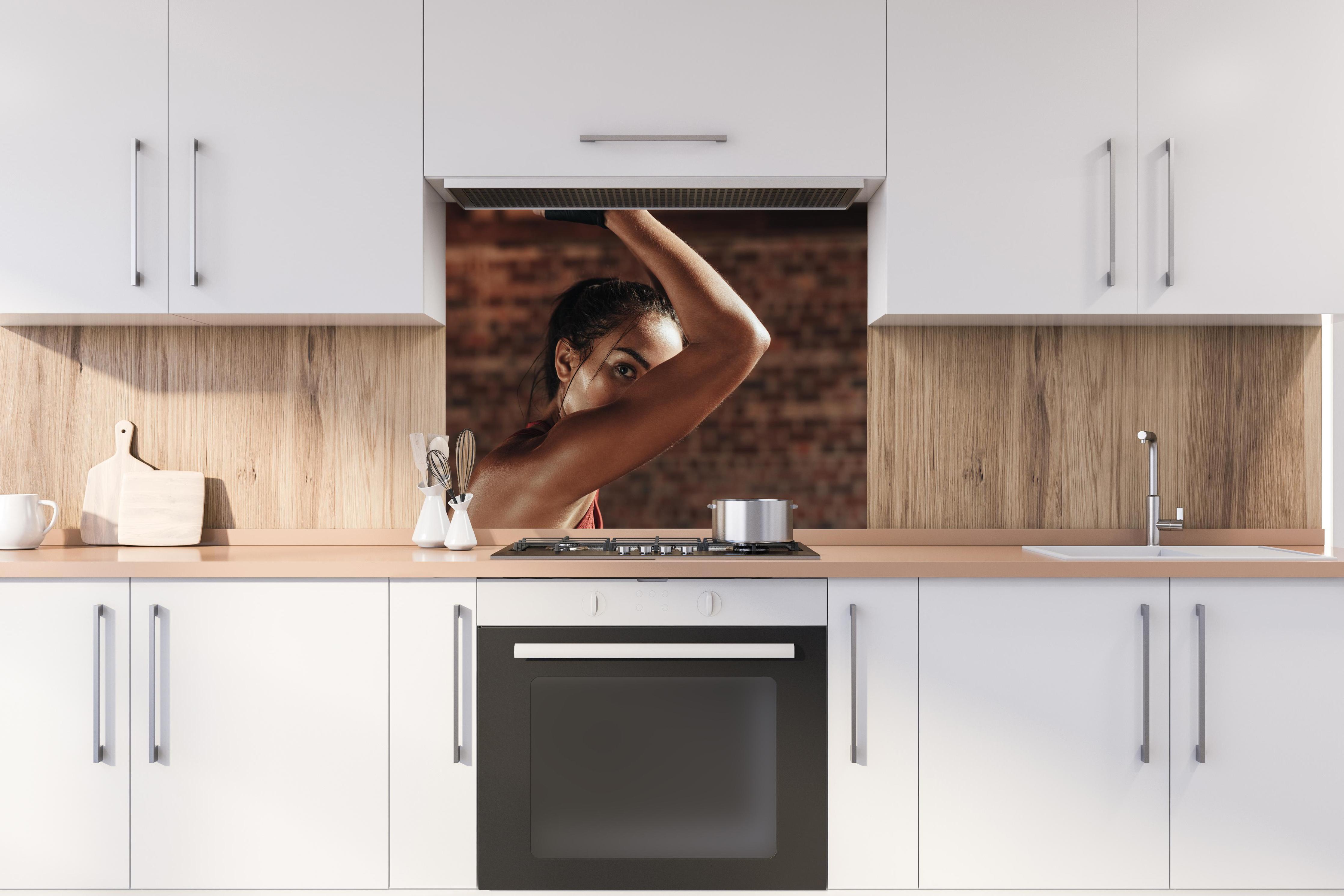 Spritzschutz - Starke Frau beim Training mit Dip-Ringen hinter stilvollem Gasherd unter Dunstabzugshaube
