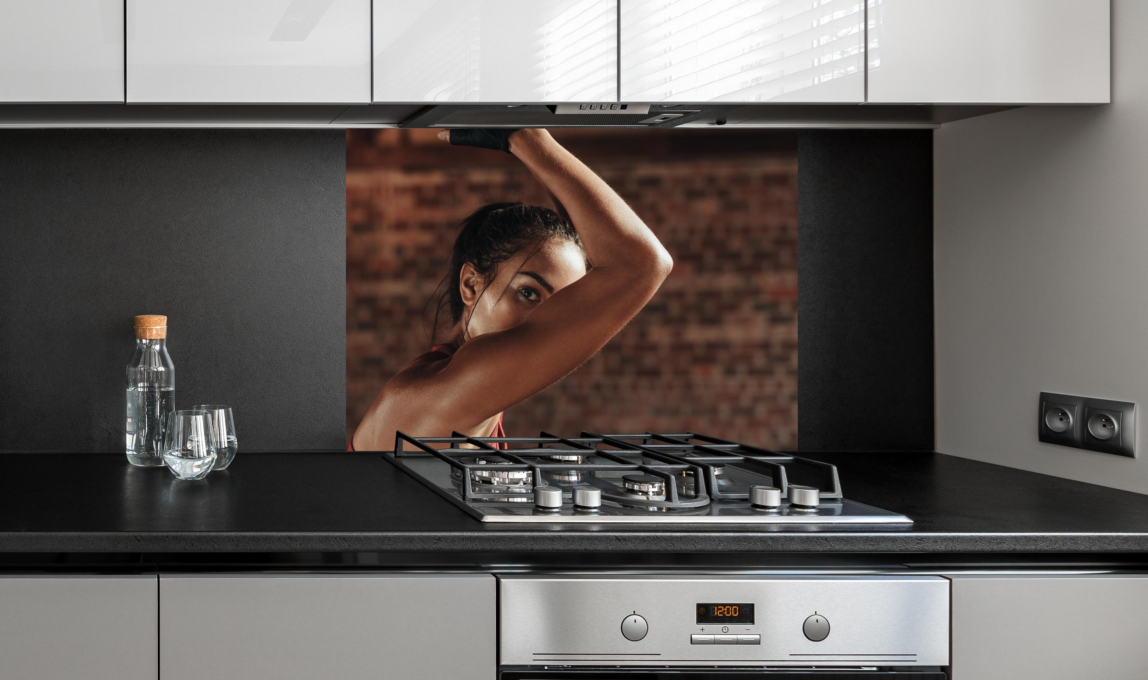 Spritzschutz - Starke Frau beim Training mit Dip-Ringen an edler Anthrazit-Wand hinter silbernem Gasherd