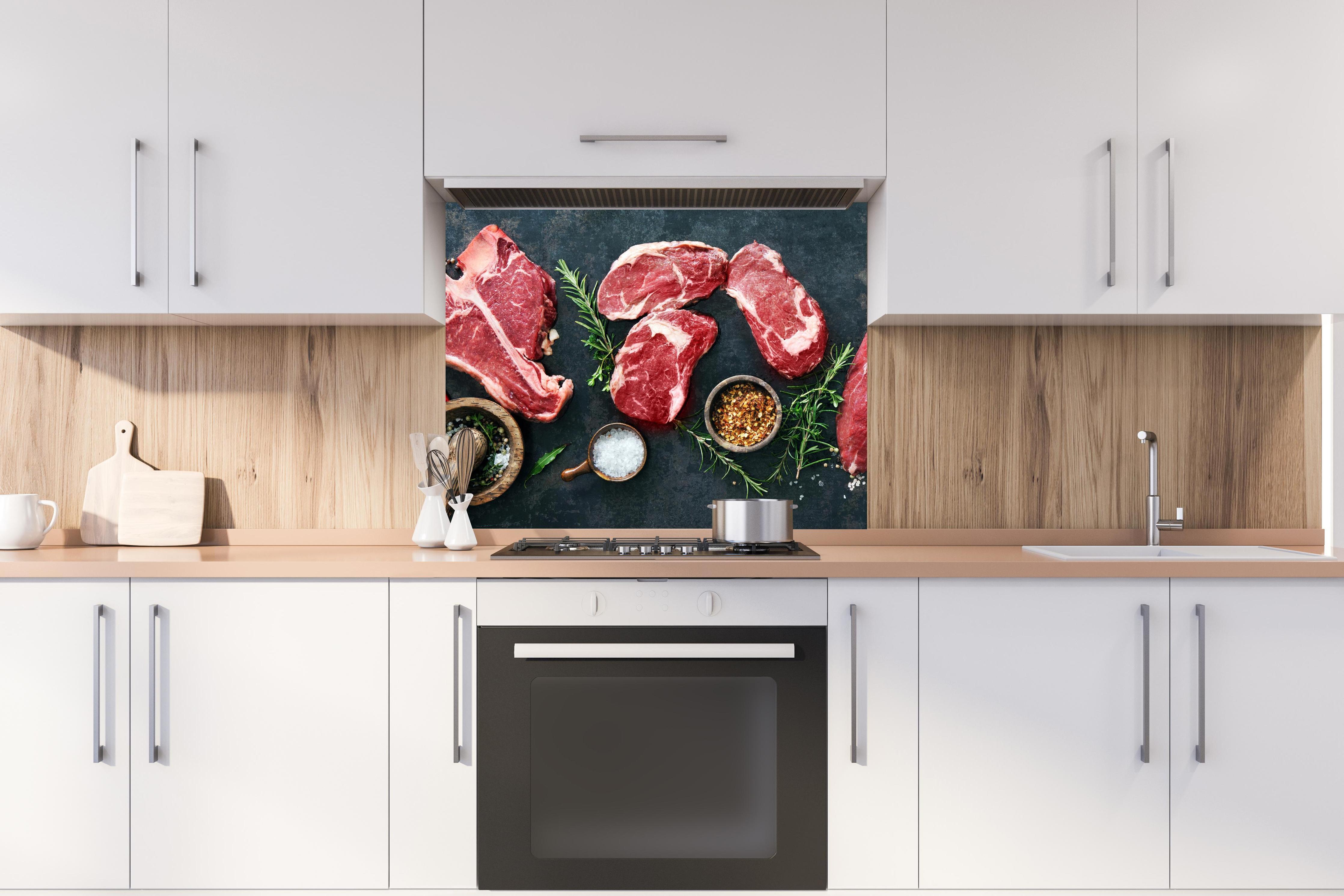 Spritzschutz - Steakvariationen auf Schieferplatte hinter stilvollem Gasherd unter Dunstabzugshaube