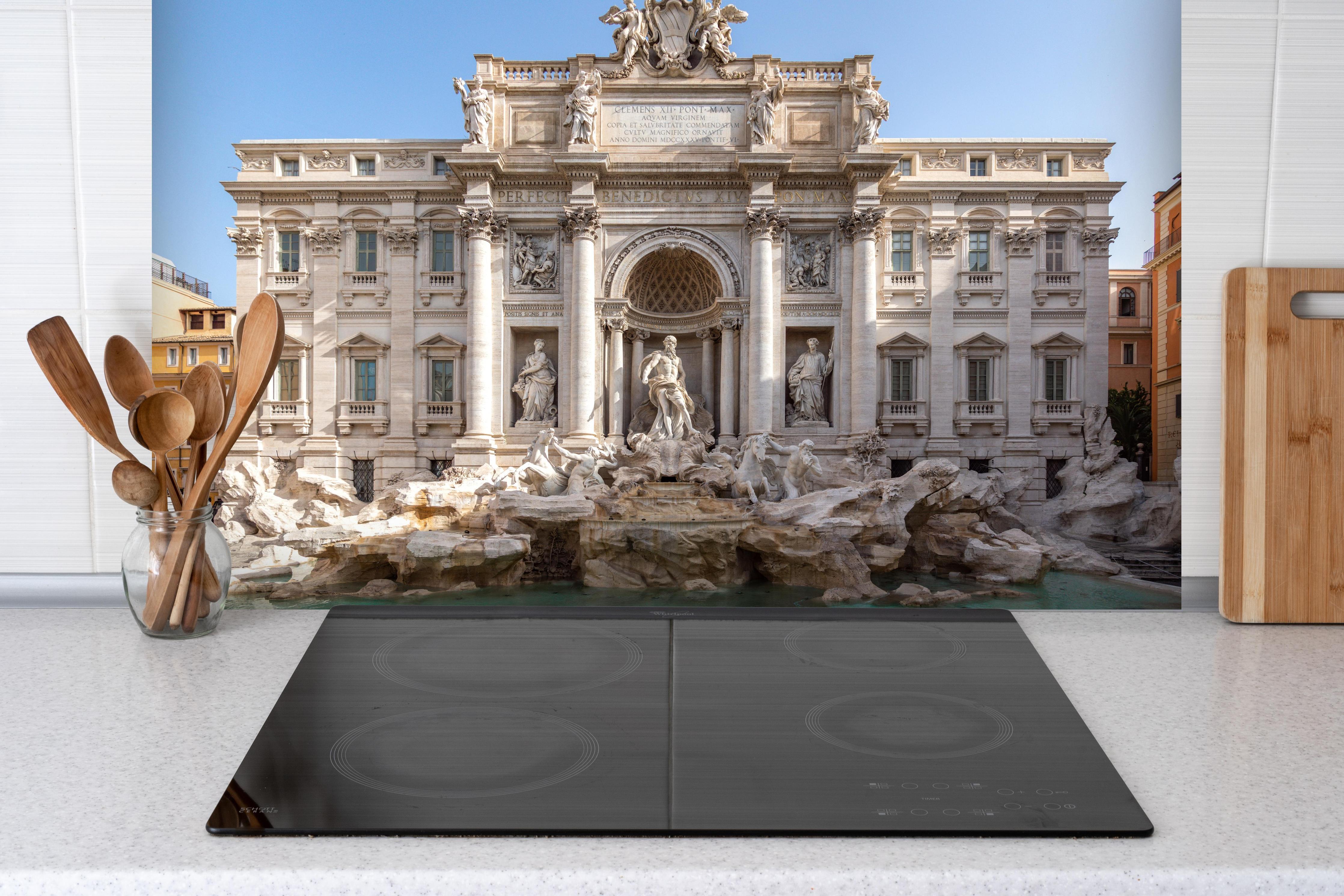 Spritzschutz - Trevi-Brunnen am Morgen in Rom hinter einem Cerankochfeld zwischen Holz-Kochutensilien
