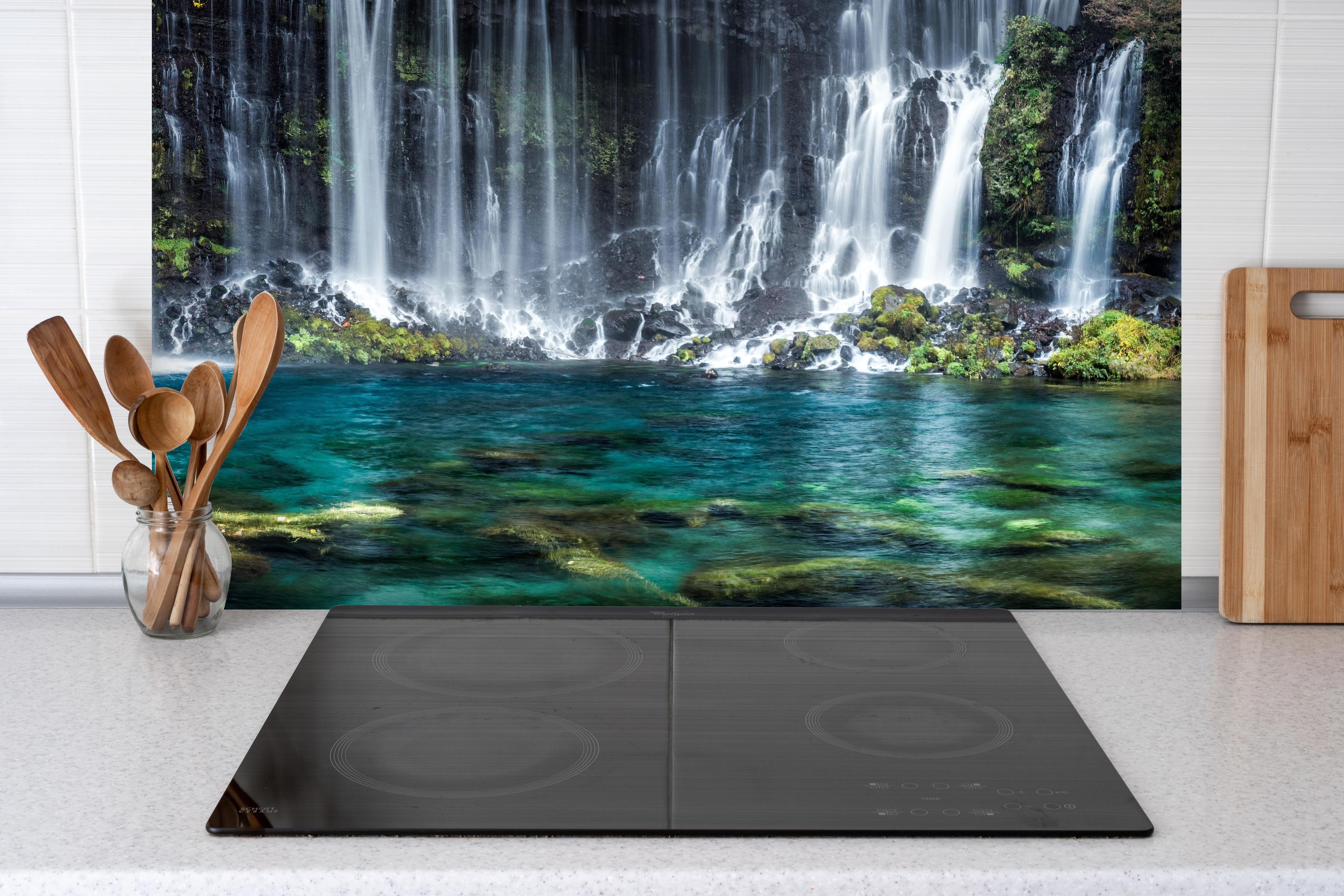 Spritzschutz - Türkisblaue Wasserfälle in Japan hinter einem Cerankochfeld zwischen Holz-Kochutensilien
