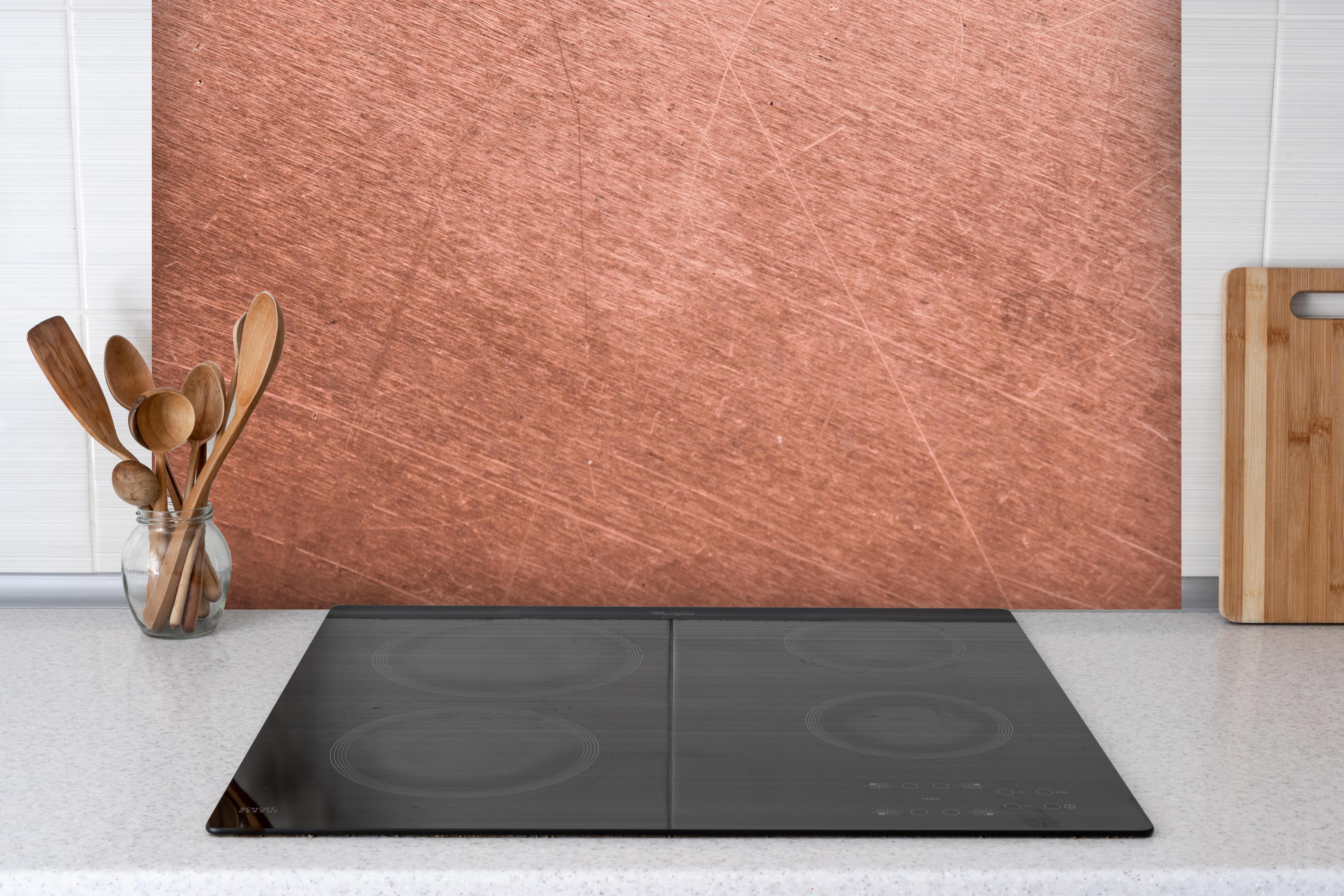 Spritzschutz - Vintage-Kupferblech hinter einem Cerankochfeld zwischen Holz-Kochutensilien
