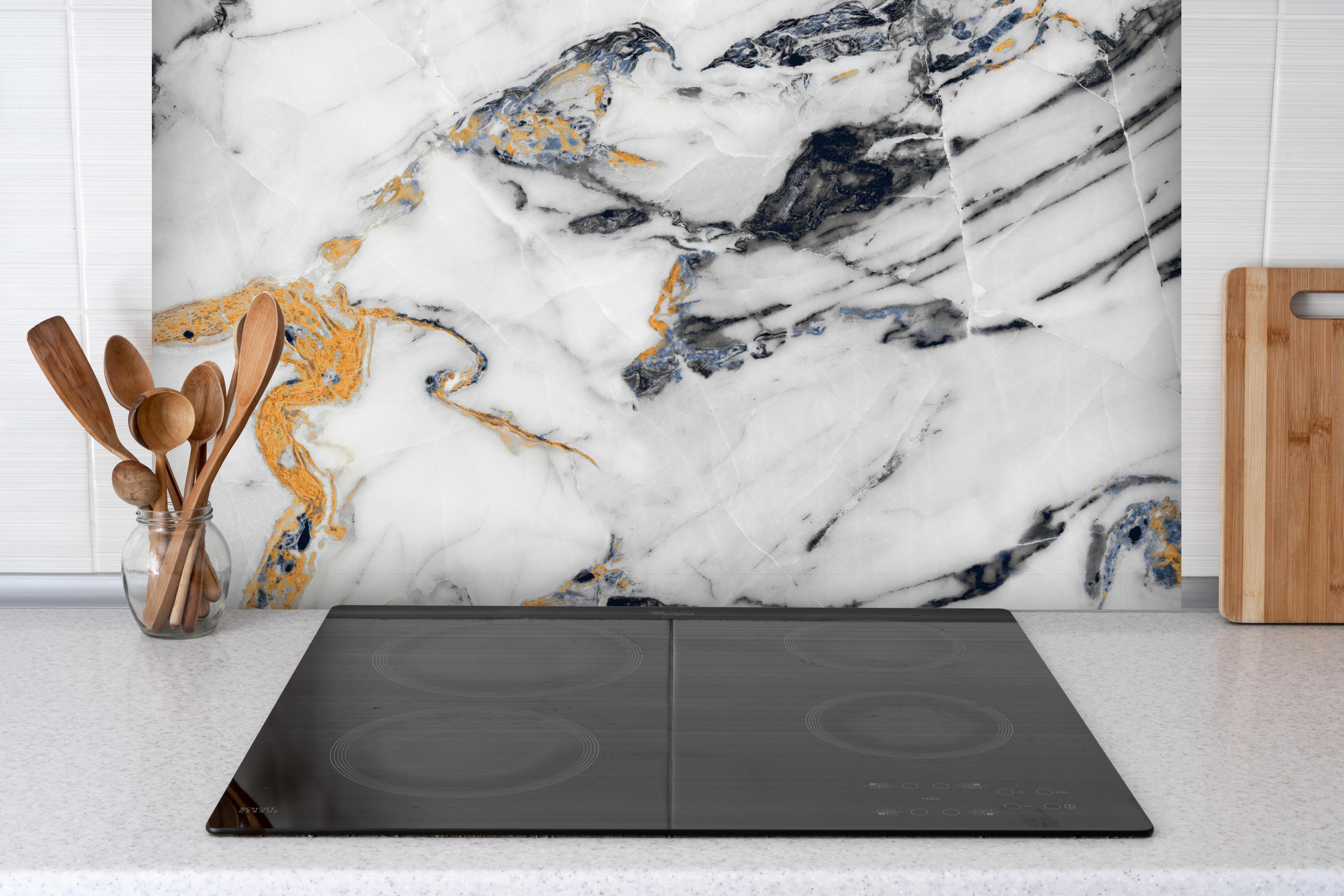 Spritzschutz - Weißer Carrara Statuario Marmor hinter einem Cerankochfeld zwischen Holz-Kochutensilien
