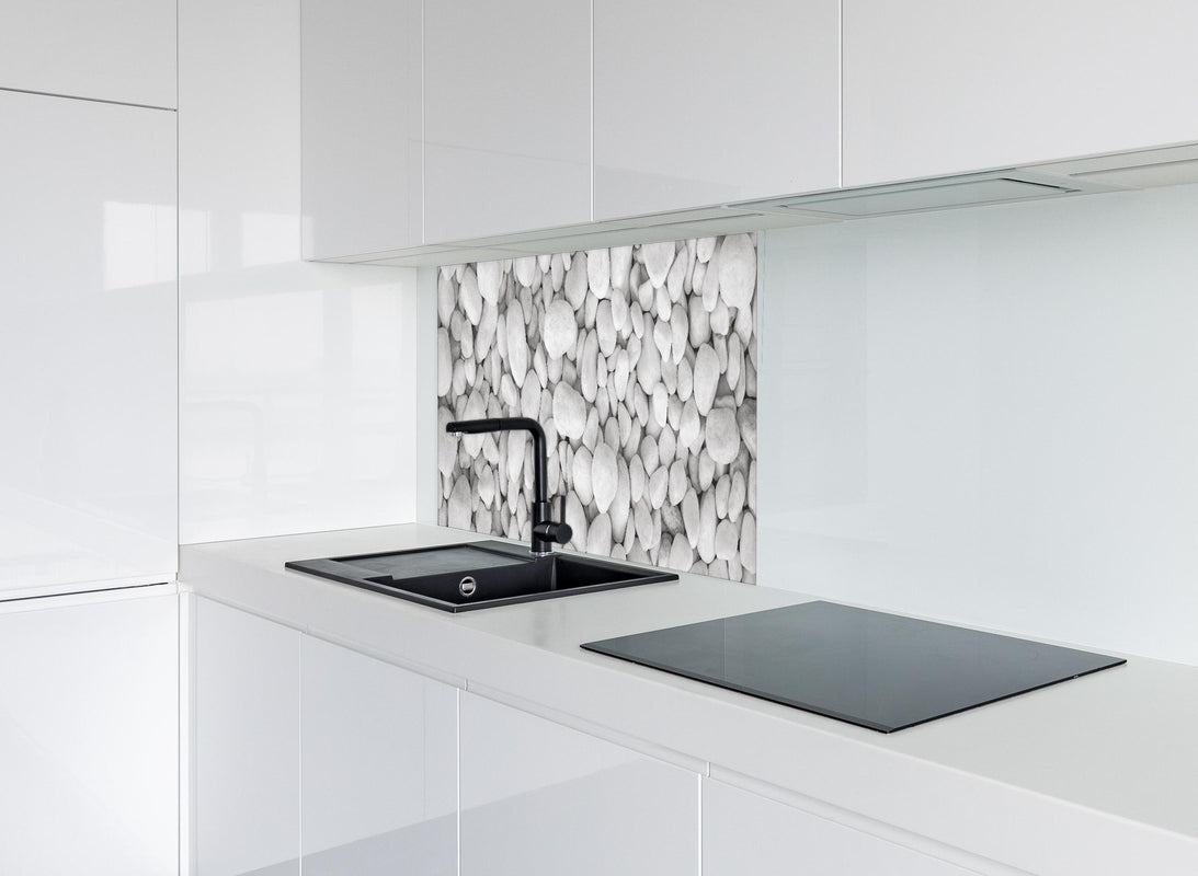 Spritzschutz - Weißer Kieselstein hinter modernem schwarz-matten Spülbecken in weißer Hochglanz-Küche