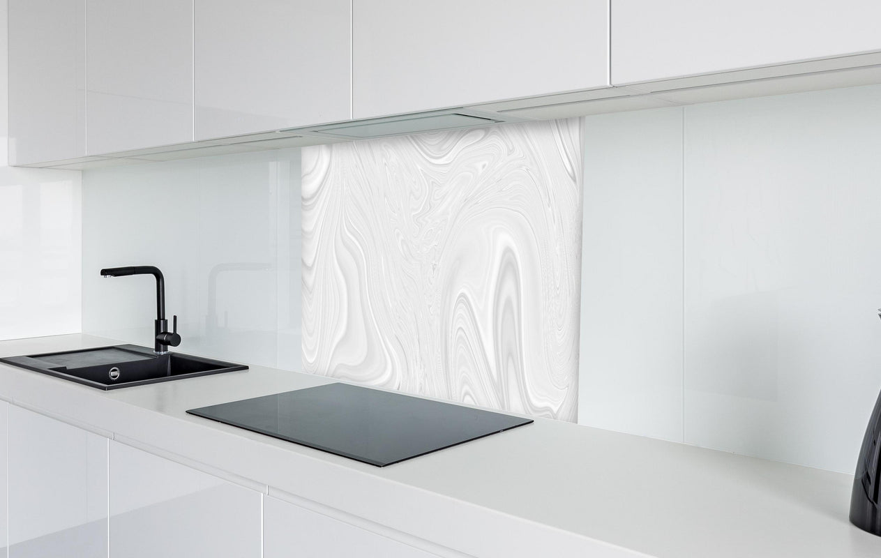 Spritzschutz - Welliger heller Marmor  in weißer Hochglanz-Küche hinter einem Cerankochfeld