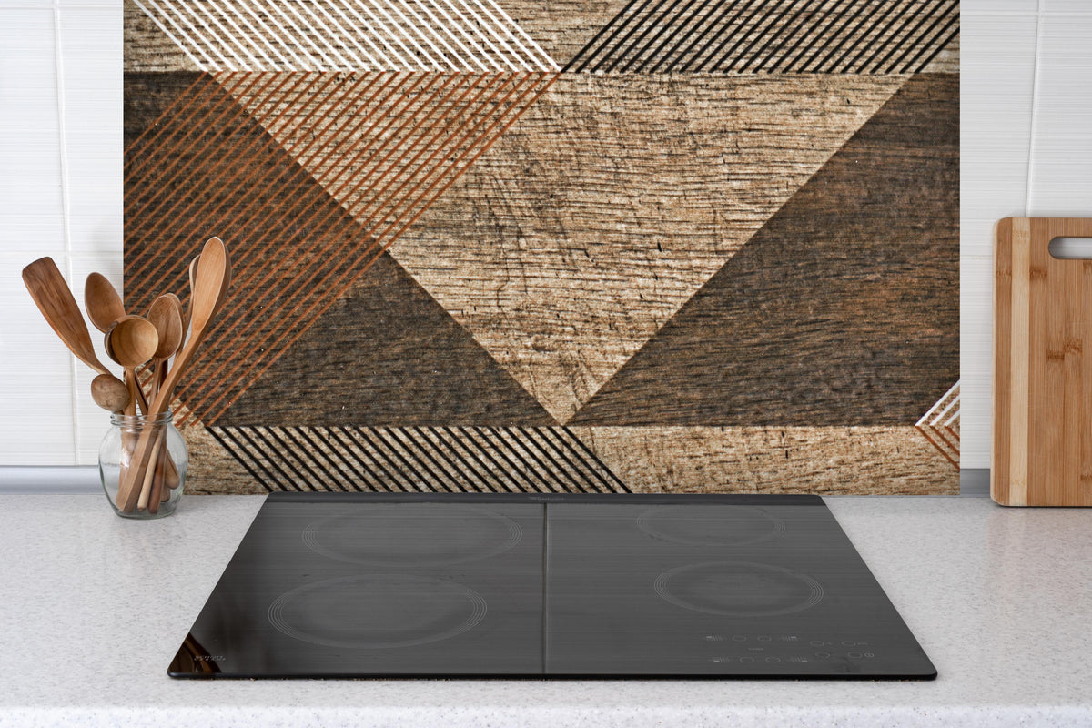 Spritzschutz - geometrisches Mosaik Design hinter einem Cerankochfeld zwischen Holz-Kochutensilien
