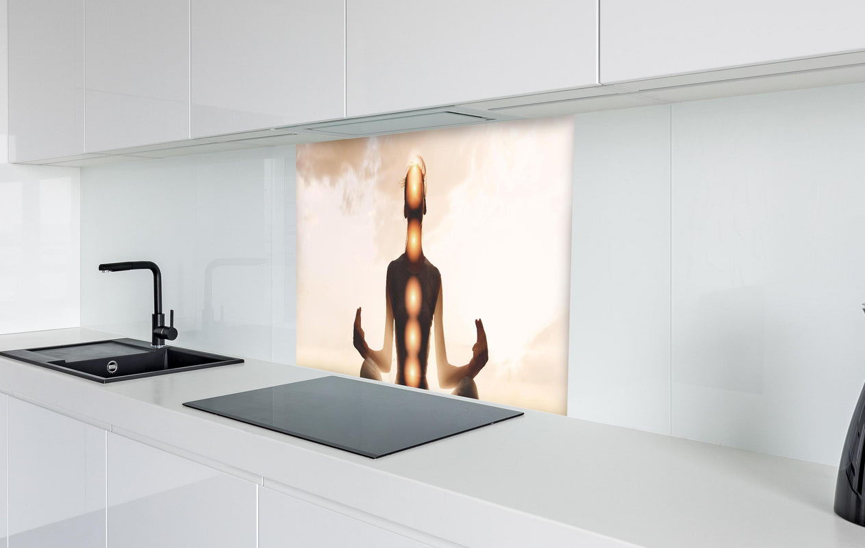 Spritzschutz - spirituelle Energie einer Frau beim Meditieren  in weißer Hochglanz-Küche hinter einem Cerankochfeld
