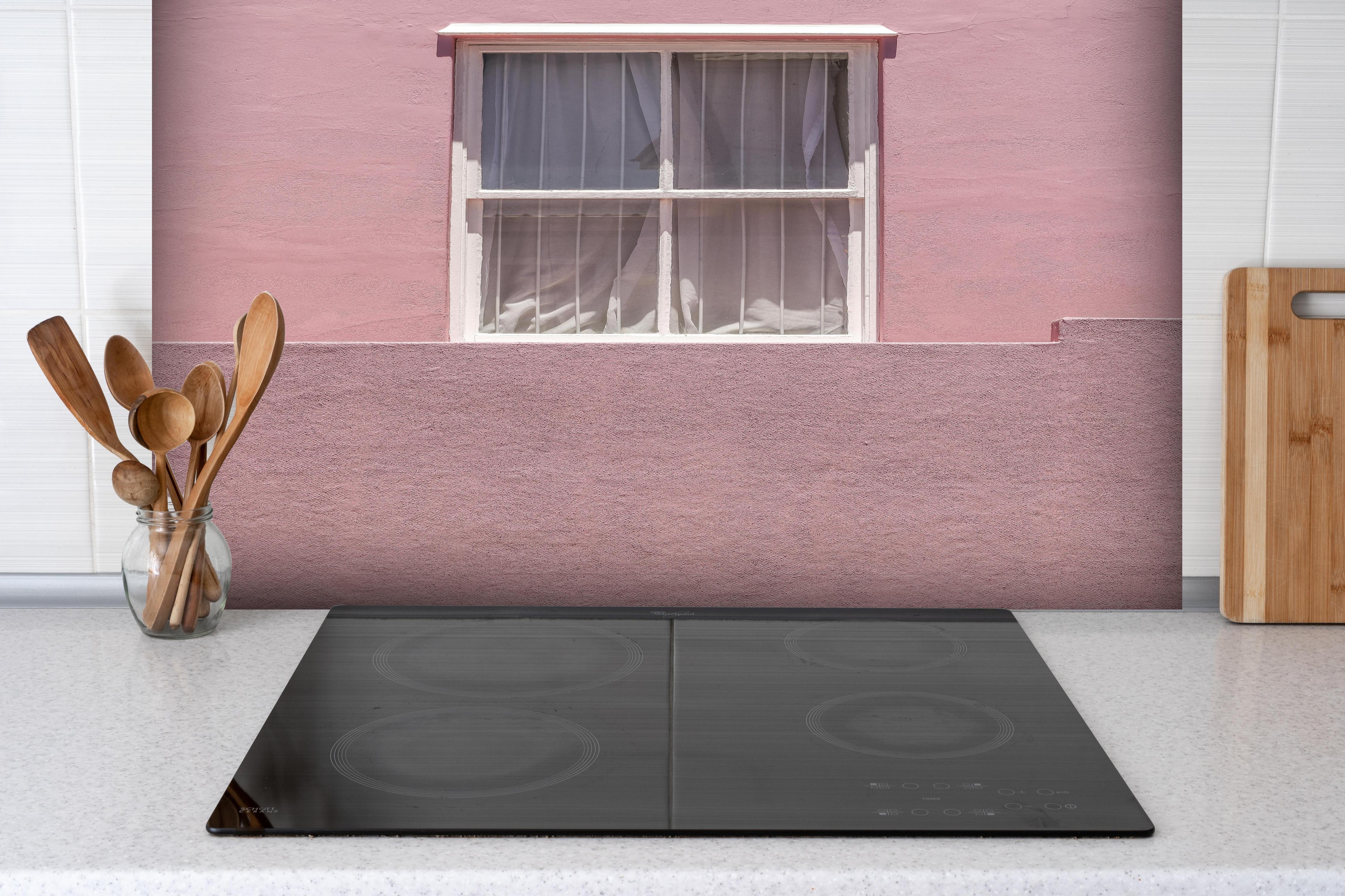 Spritzschutz - Städtische Pinkfarbene Wand mit Fenster hinter einem Cerankochfeld zwischen Holz-Kochutensilien
