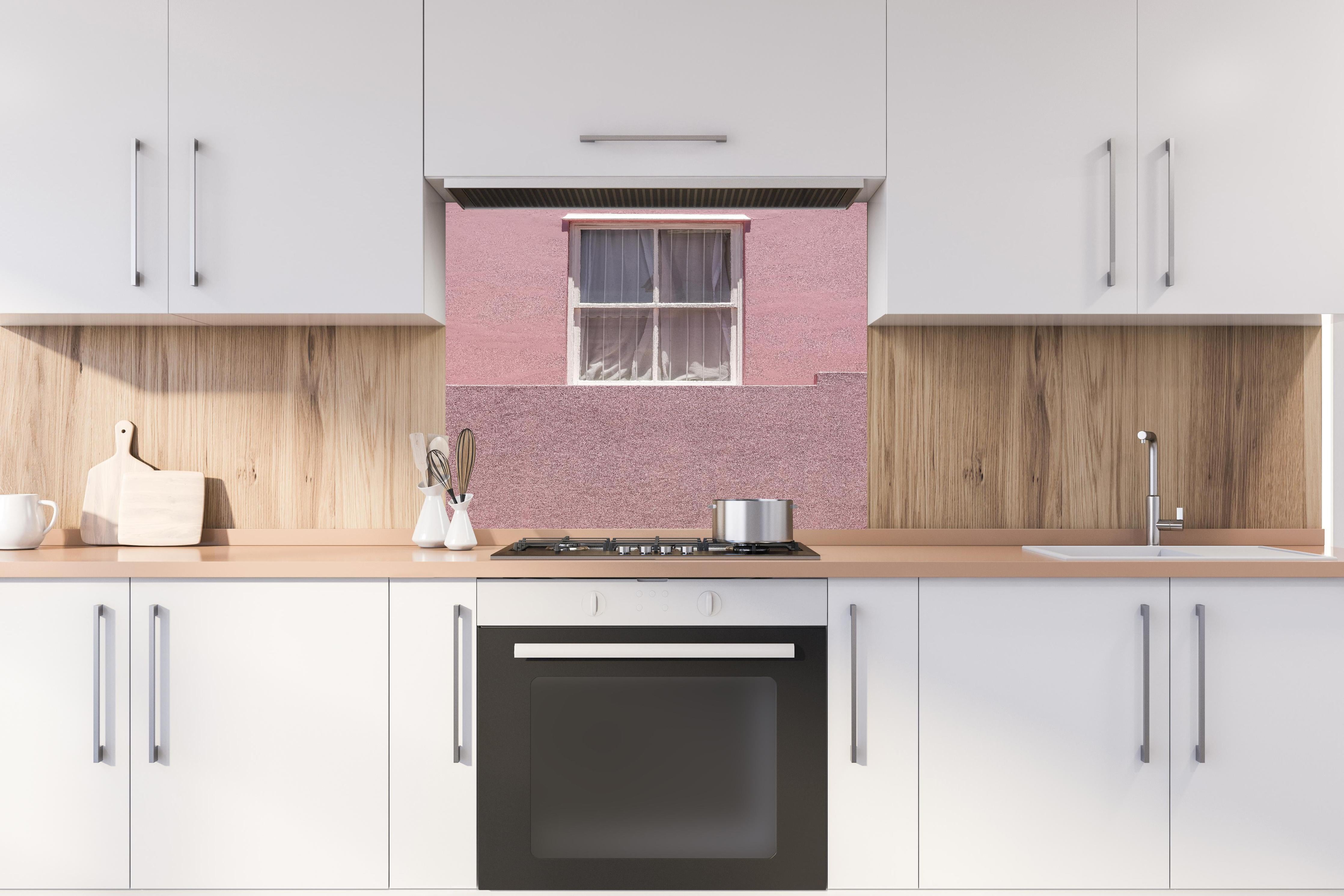 Spritzschutz - Städtische Pinkfarbene Wand mit Fenster hinter einem Cerankochfeld zwischen Holz-Kochutensilien
