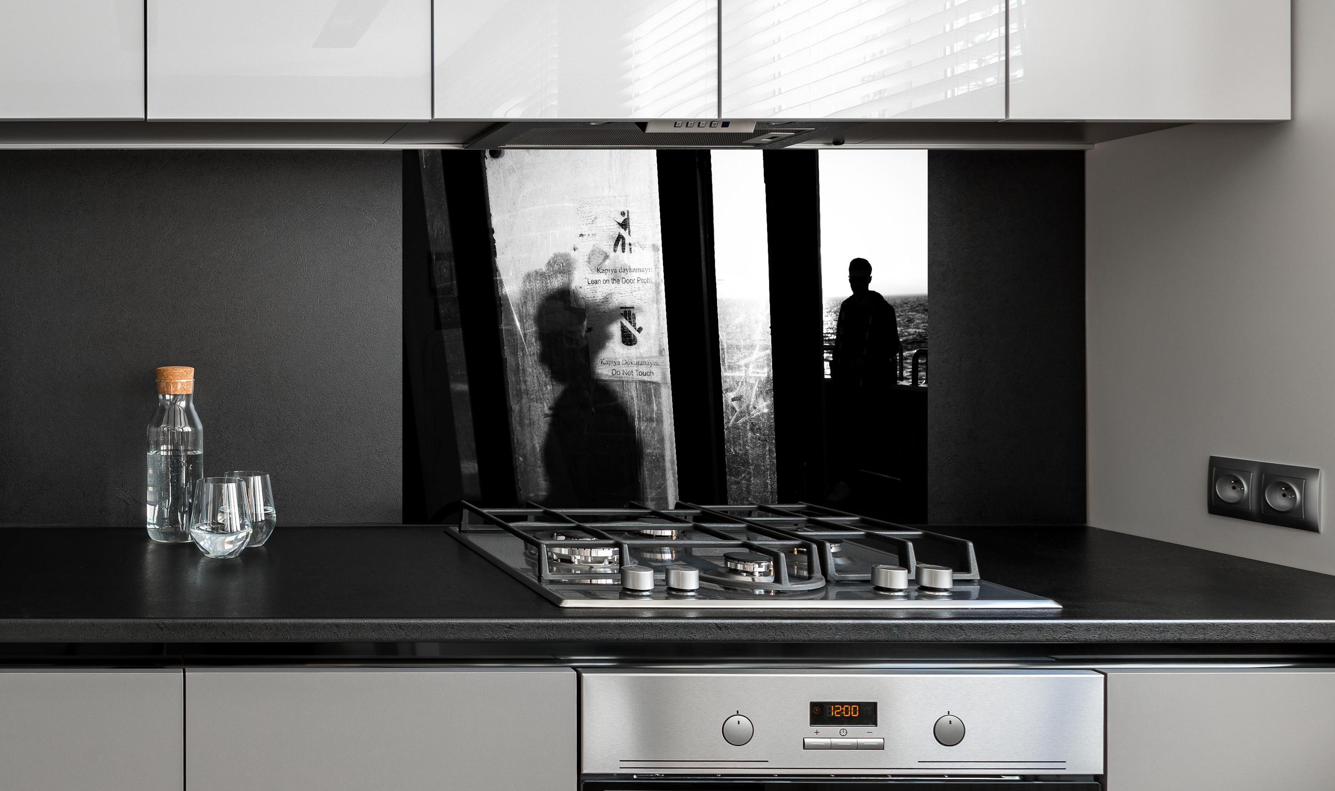 Spritzschutz - Städtisches Bild mit Silhouetten hinter einem Cerankochfeld zwischen Holz-Kochutensilien

