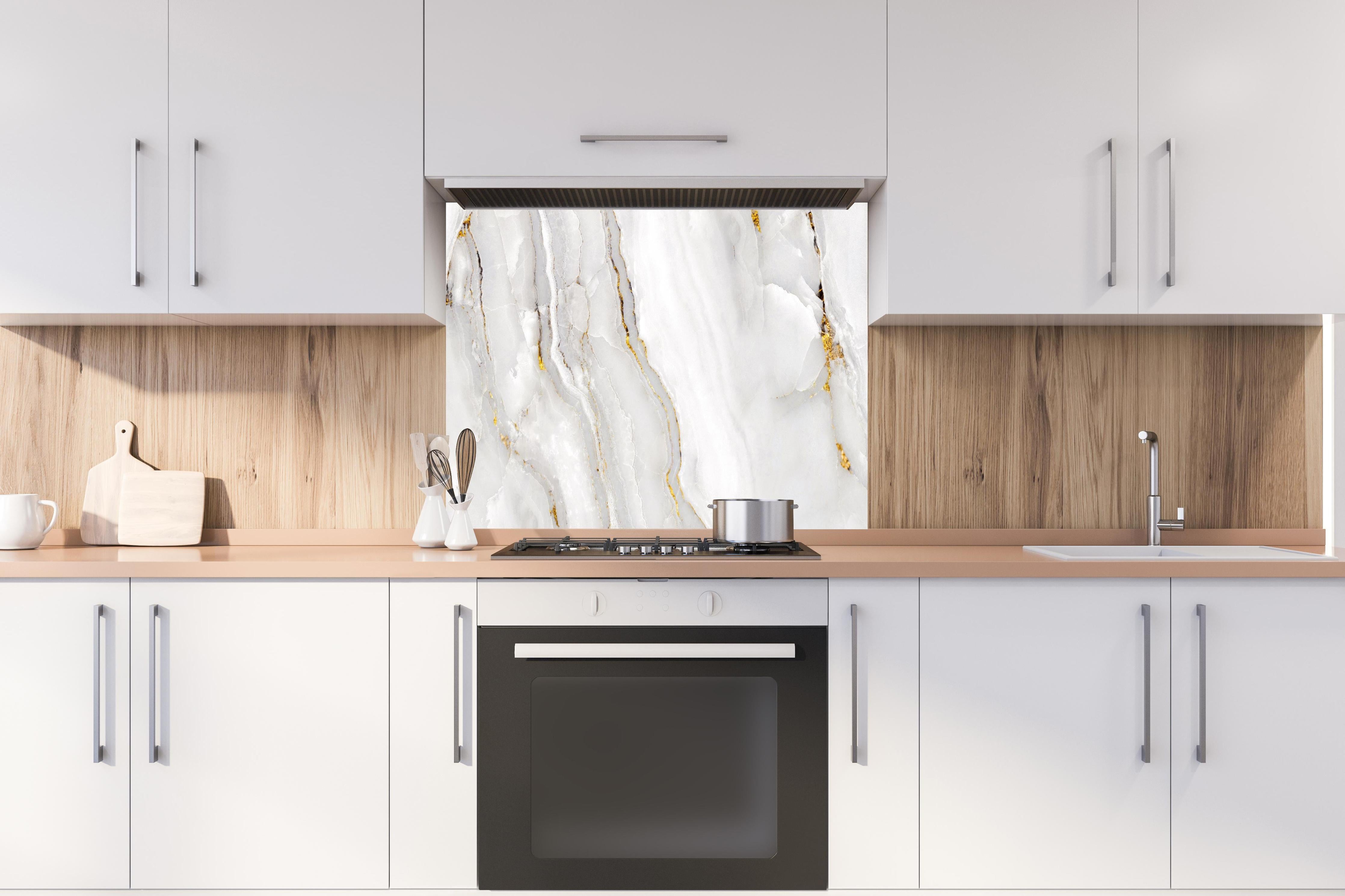 Spritzschutz - Statuario Marmor mit goldenen Akzenten hinter einem Cerankochfeld zwischen Holz-Kochutensilien
