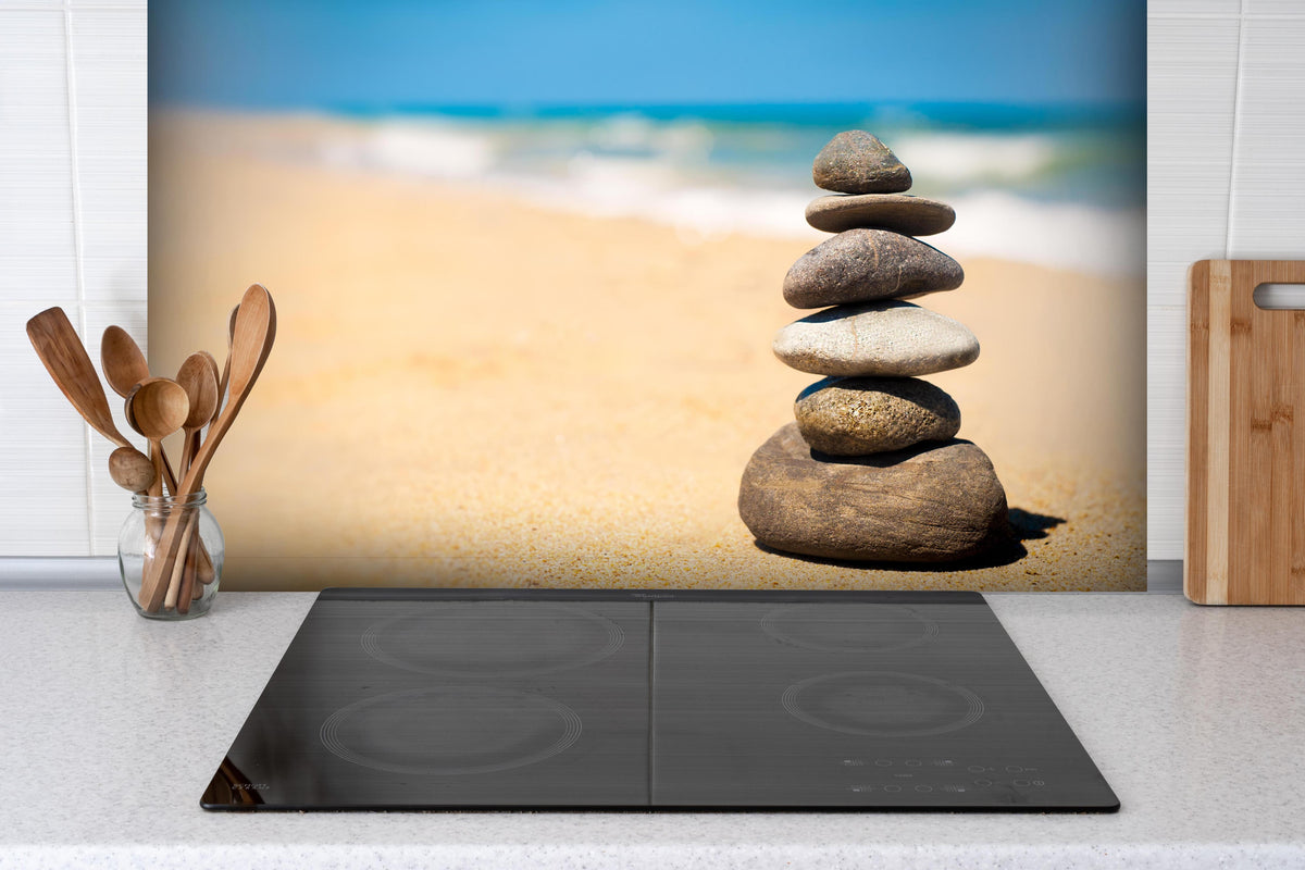 Spritzschutz - Steine Meditation Balance hinter einem Cerankochfeld zwischen Holz-Kochutensilien
