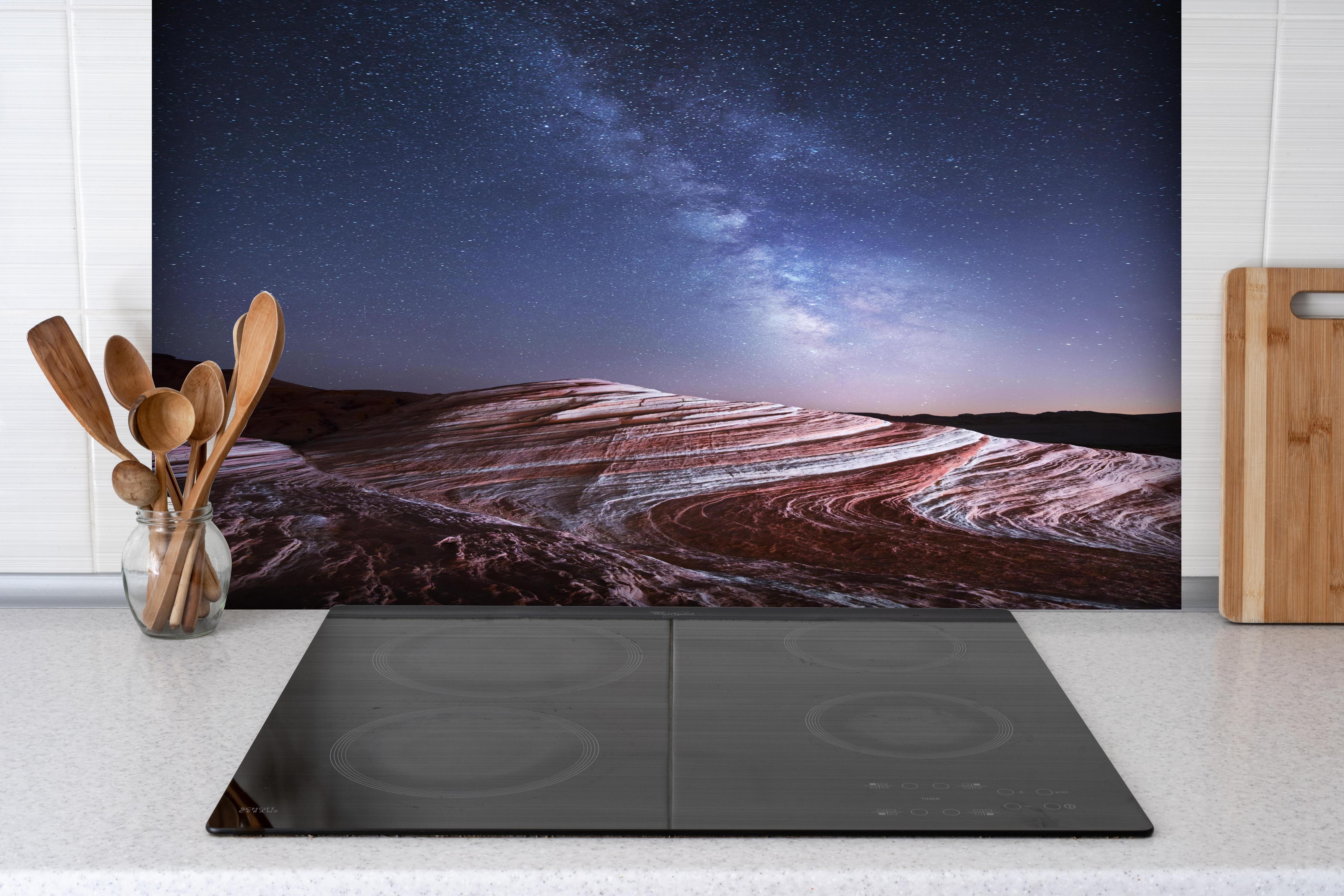 Spritzschutz - Sterne über rot-gestreifter Berglandschaft hinter einem Cerankochfeld zwischen Holz-Kochutensilien
