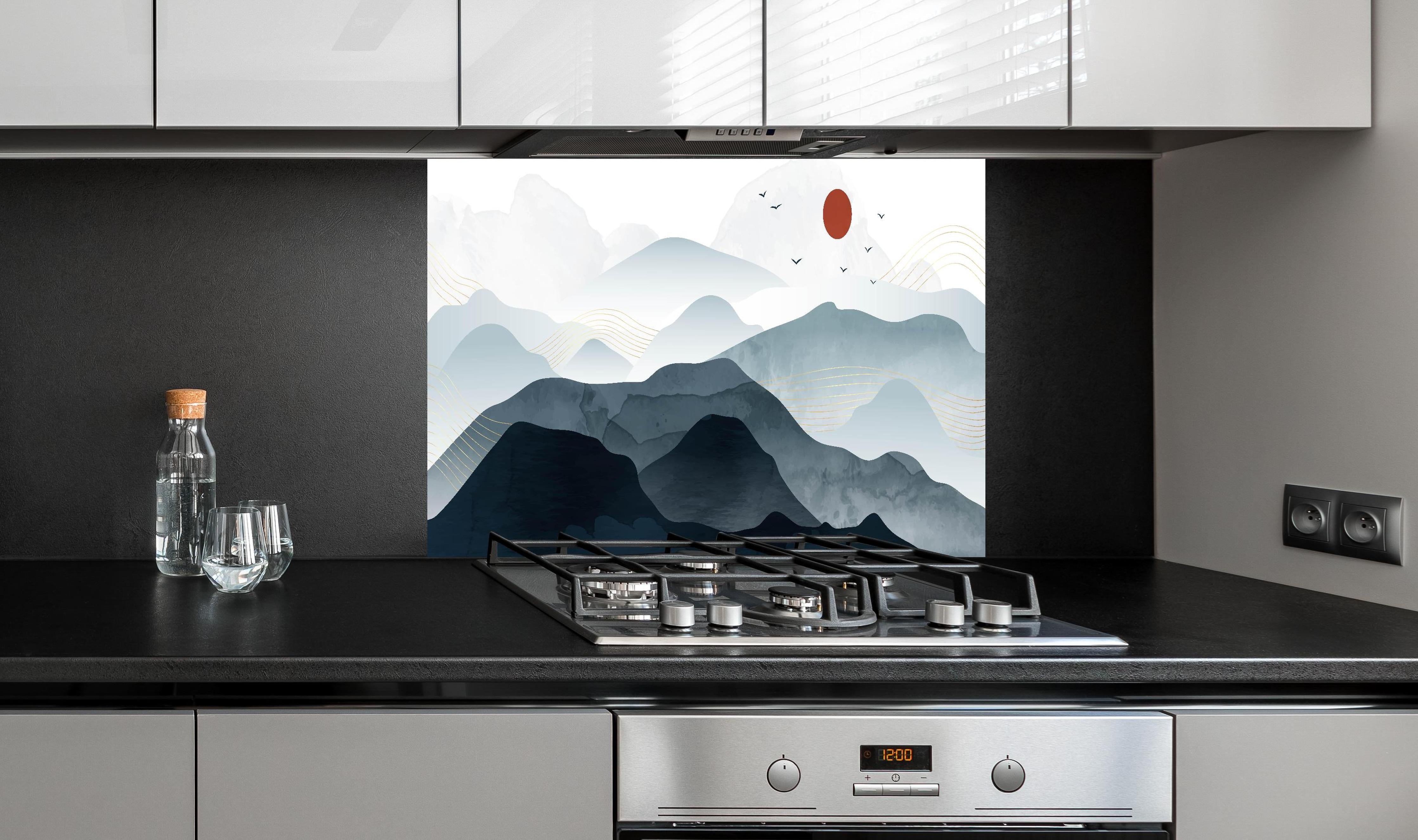 Spritzschutz - Stilisierte Berge unter Roter Sonne hinter einem Cerankochfeld zwischen Holz-Kochutensilien
