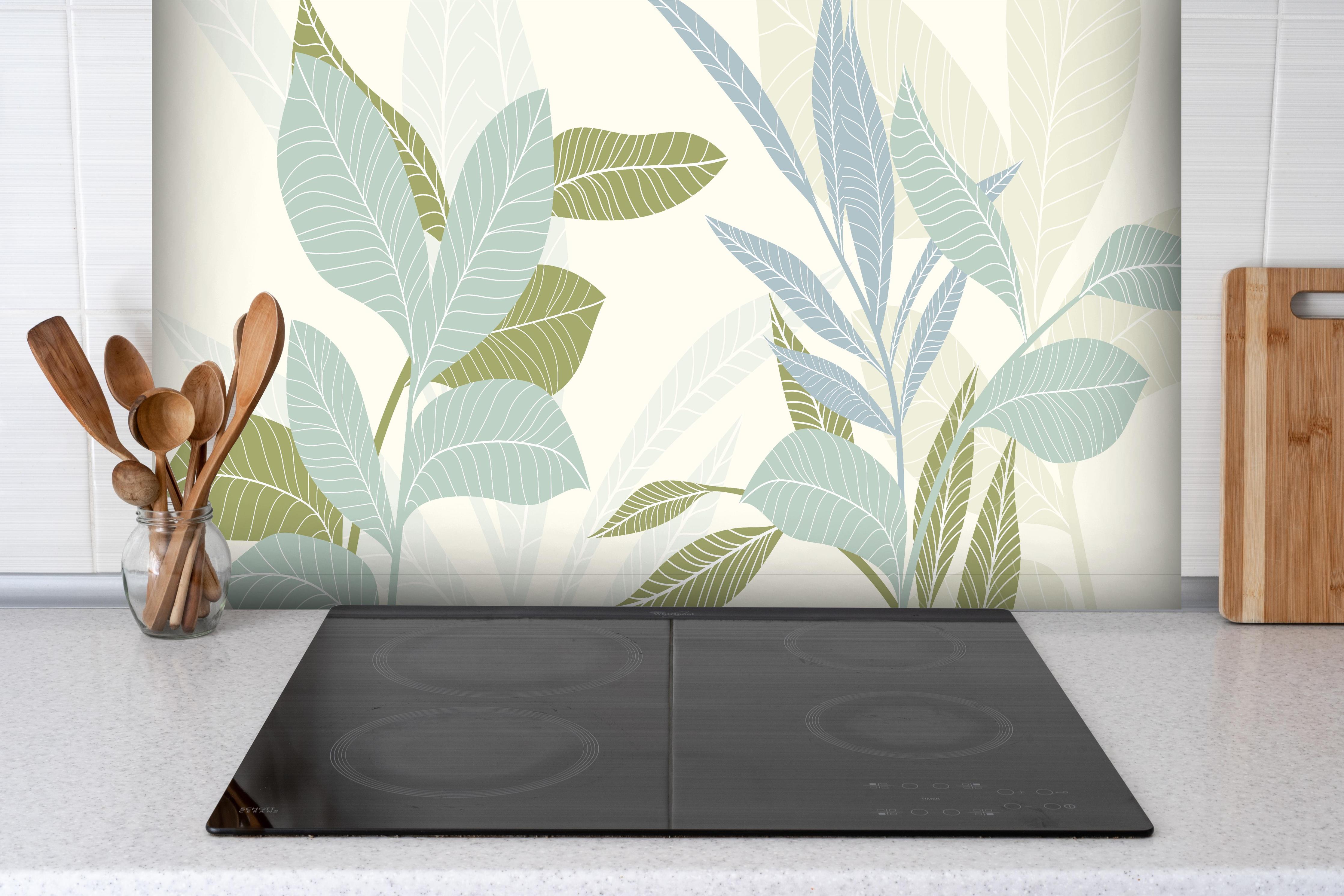 Spritzschutz - Stilvolles Blatt-Design in Pastelltönen hinter einem Cerankochfeld zwischen Holz-Kochutensilien
