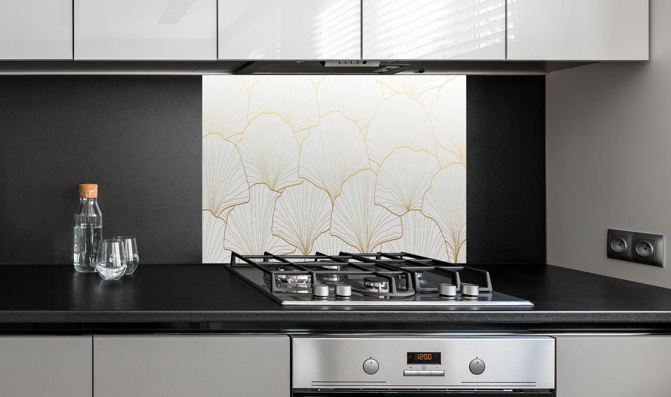 Spritzschutz - Stilvolles Ginkgo Muster Weiß-Gold Tapete hinter einem Cerankochfeld zwischen Holz-Kochutensilien
