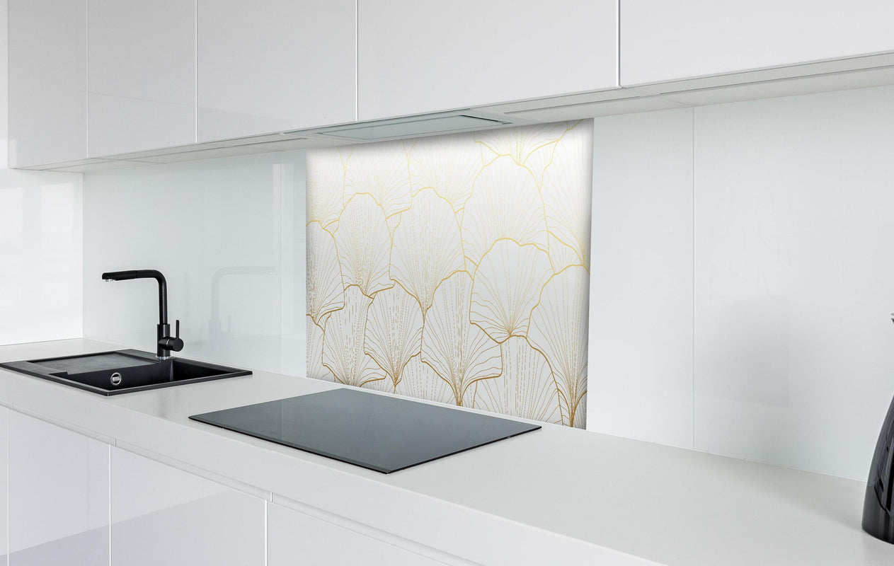 Spritzschutz - Stilvolles Ginkgo Muster Weiß-Gold Tapete hinter einem Cerankochfeld zwischen Holz-Kochutensilien
