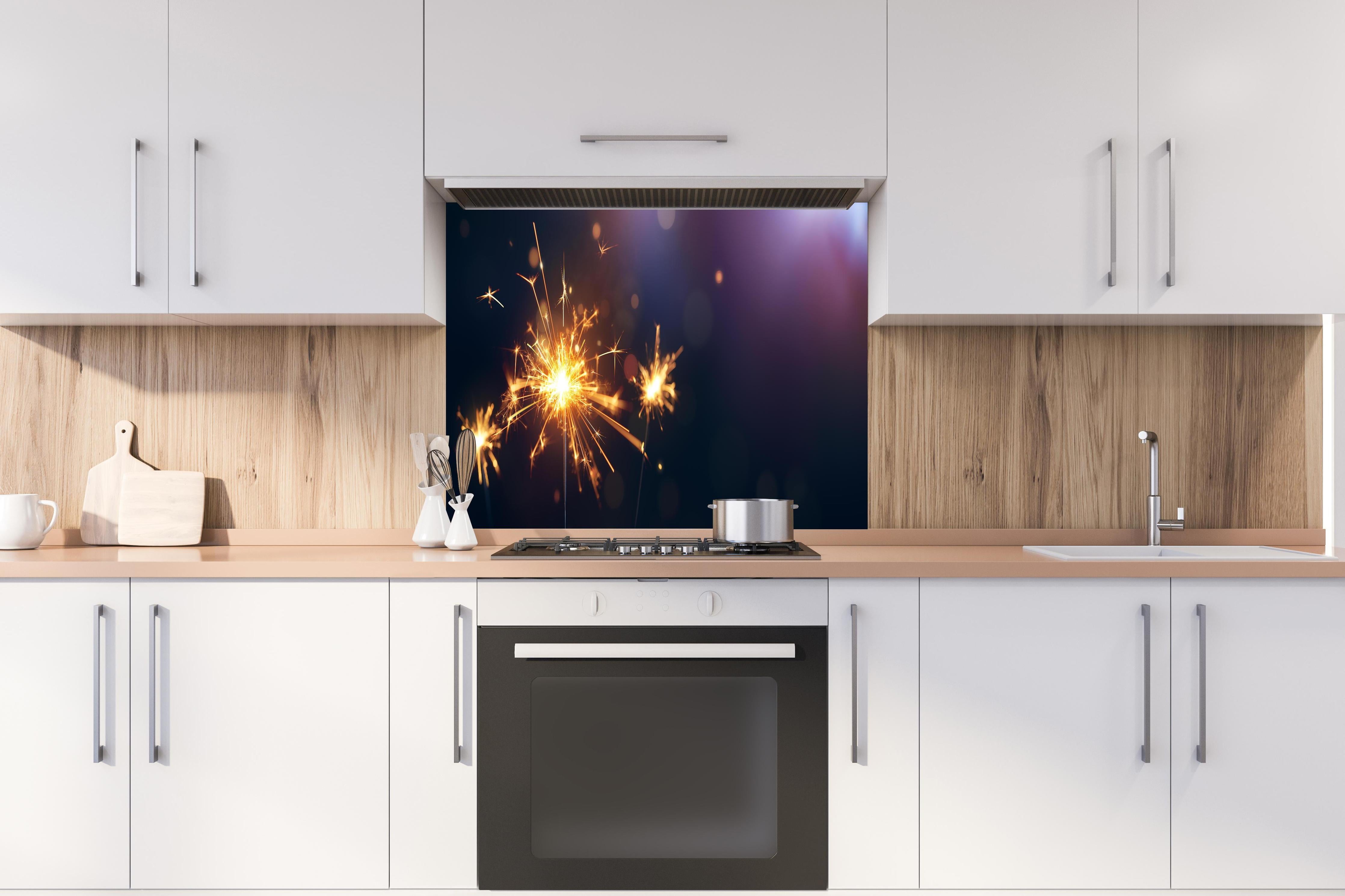 Spritzschutz - Strahlendes Wunderkerzen-Goldlichtfeuerwerk hinter einem Cerankochfeld zwischen Holz-Kochutensilien
