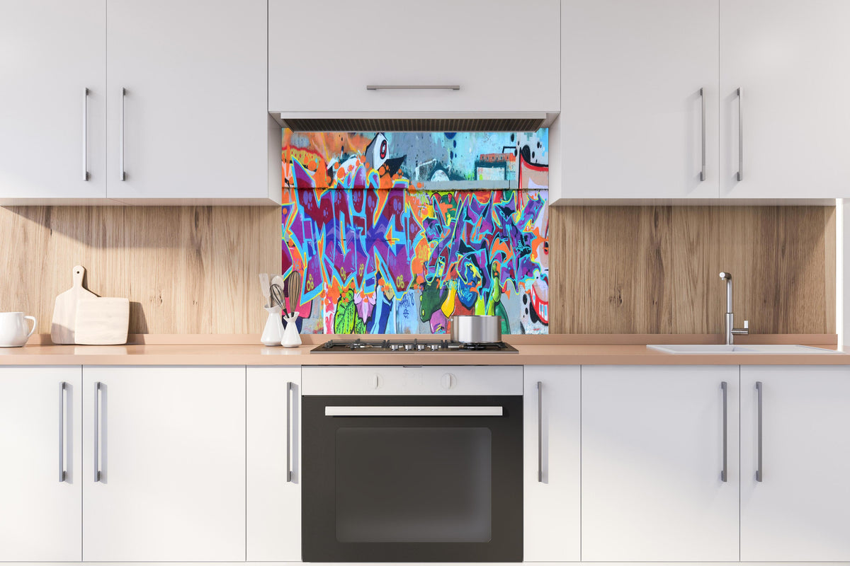 Spritzschutz - Street Art Graffiti in Lila-Tönen hinter einem Cerankochfeld zwischen Holz-Kochutensilien
