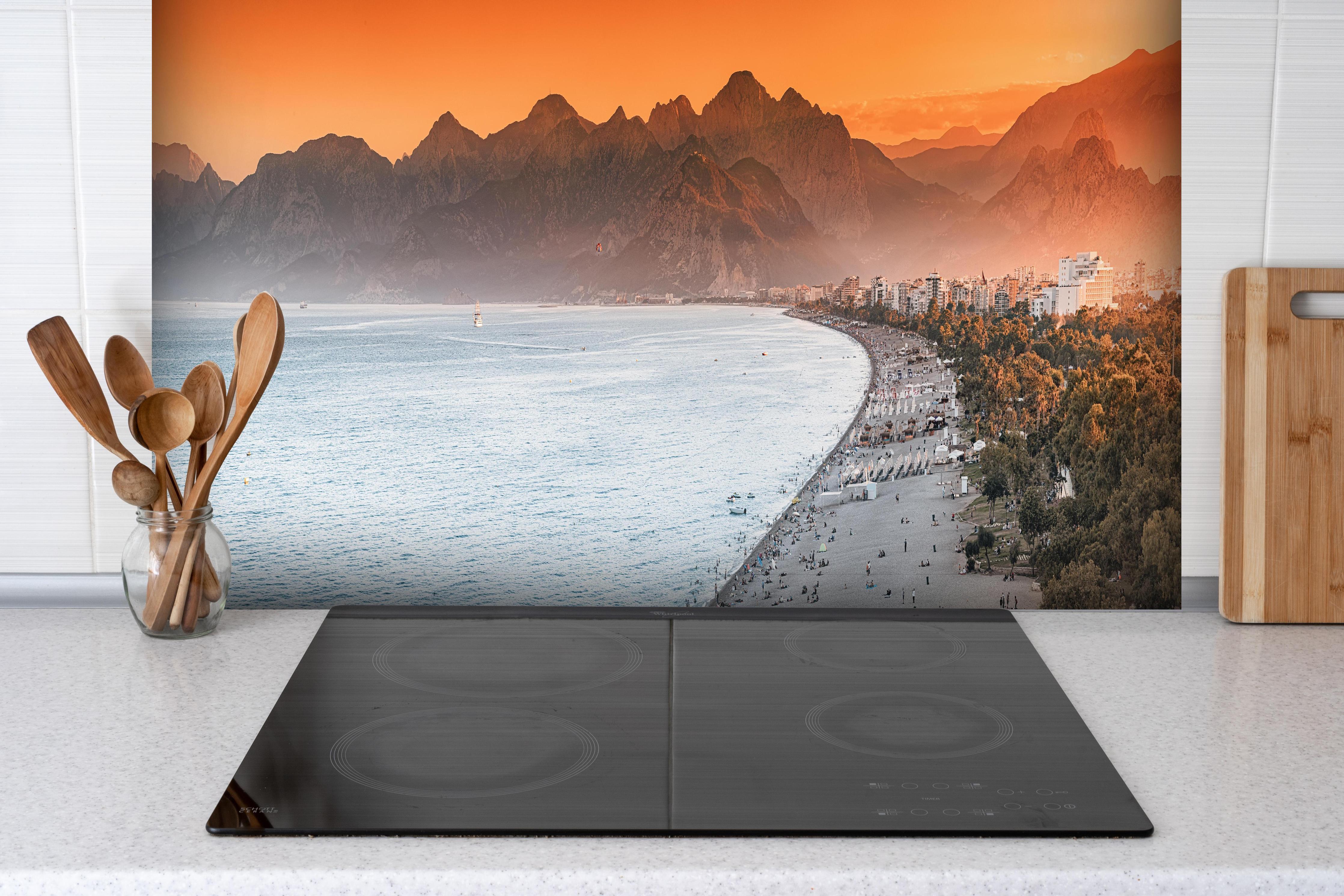 Spritzschutz - Sunset Konyaalti Beach Antalya Türkei hinter einem Cerankochfeld zwischen Holz-Kochutensilien
