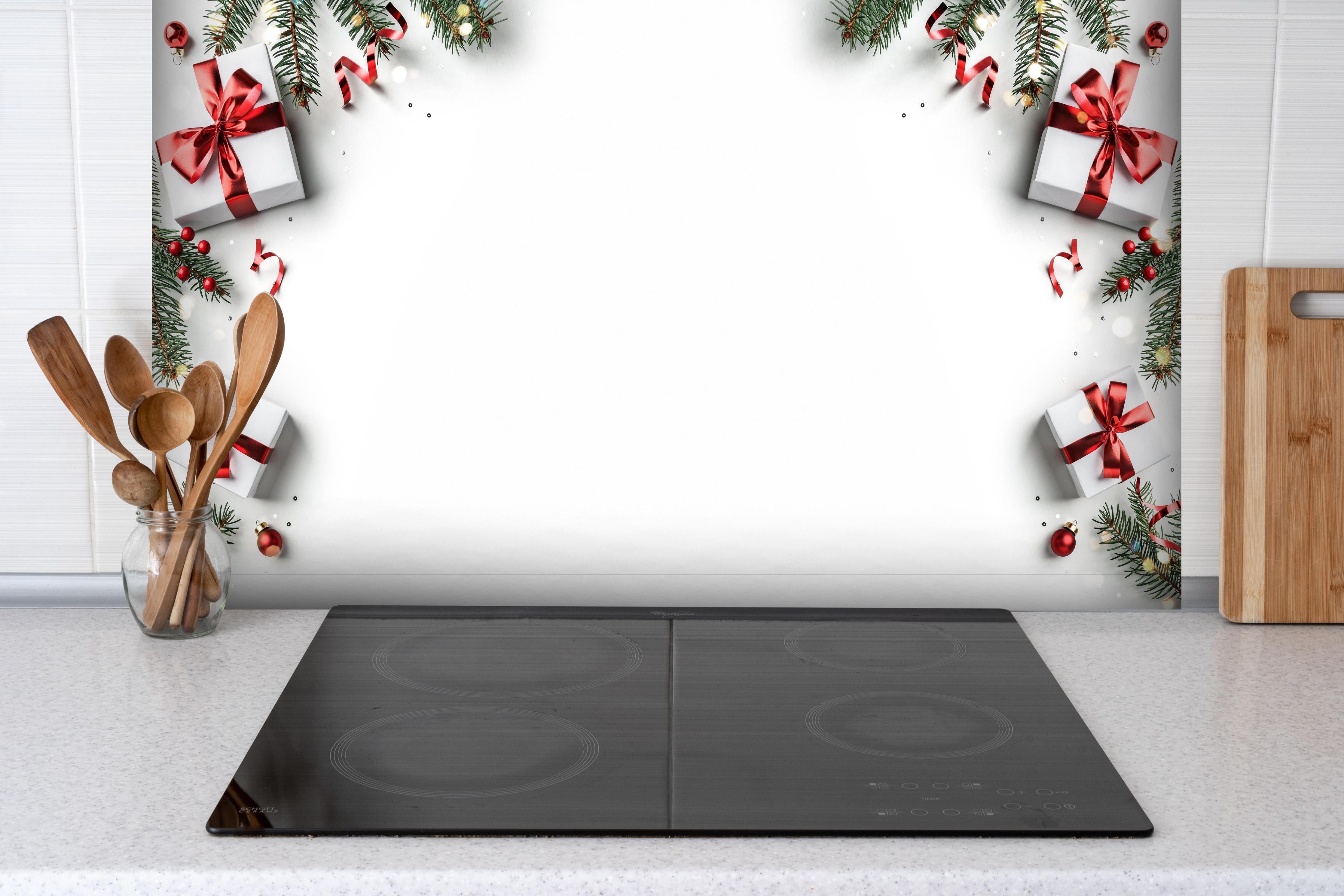 Spritzschutz - Tannenzweige als Rahmen hinter einem Cerankochfeld zwischen Holz-Kochutensilien
