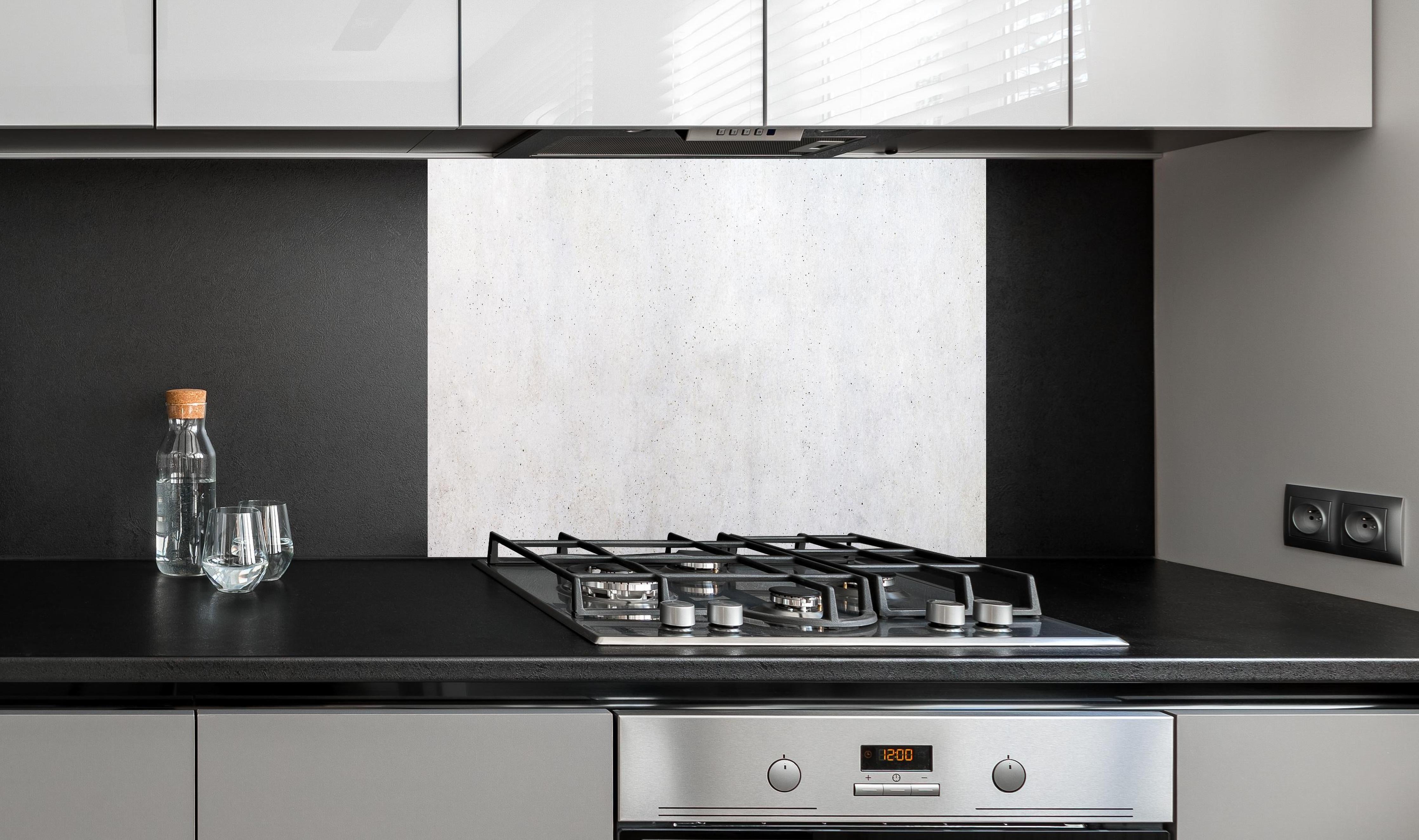 Spritzschutz - Textur einer weißen Betonwand hinter einem Cerankochfeld zwischen Holz-Kochutensilien
