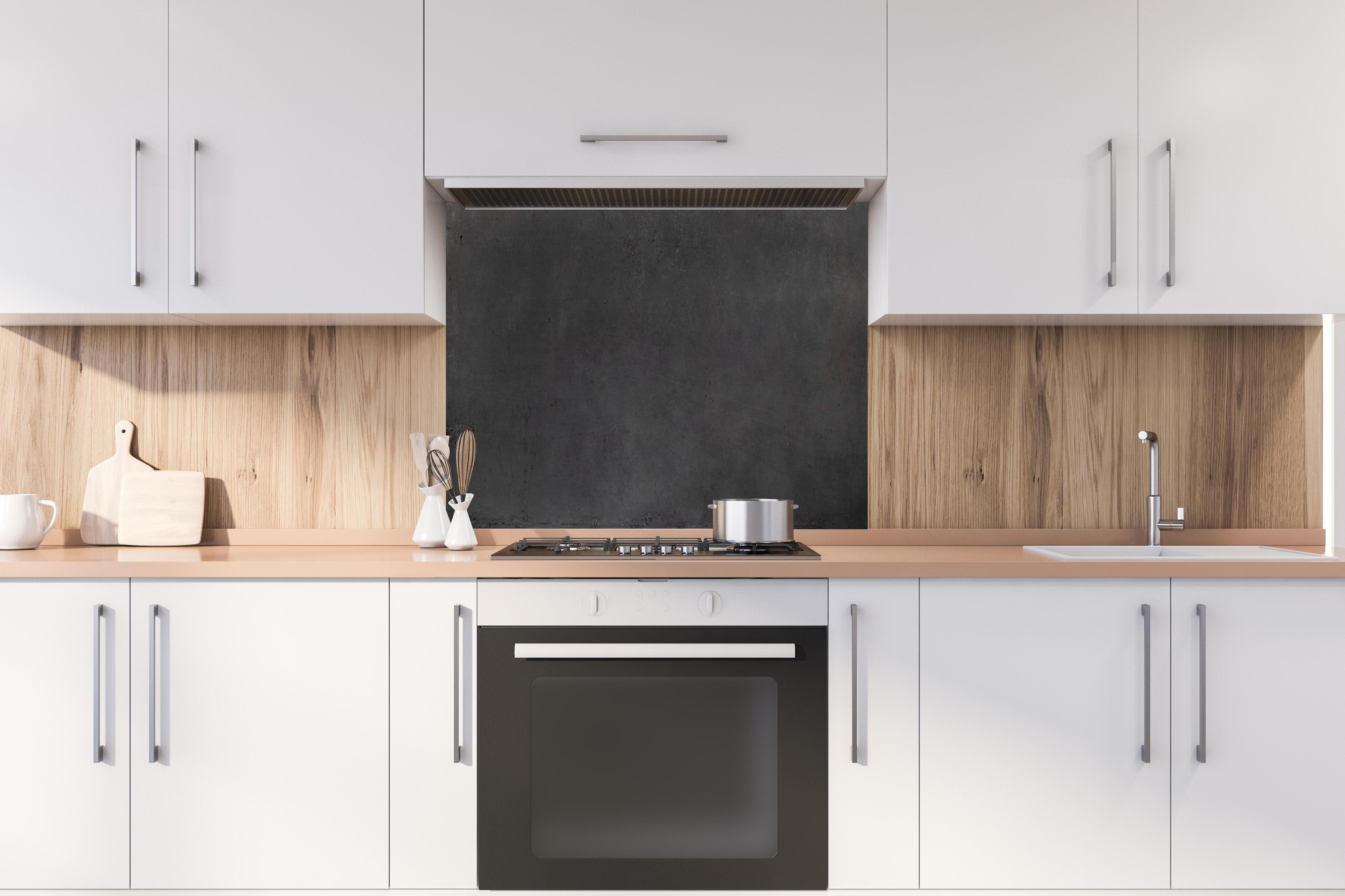 Spritzschutz - Textur von poliertem Beton hinter einem Cerankochfeld zwischen Holz-Kochutensilien
